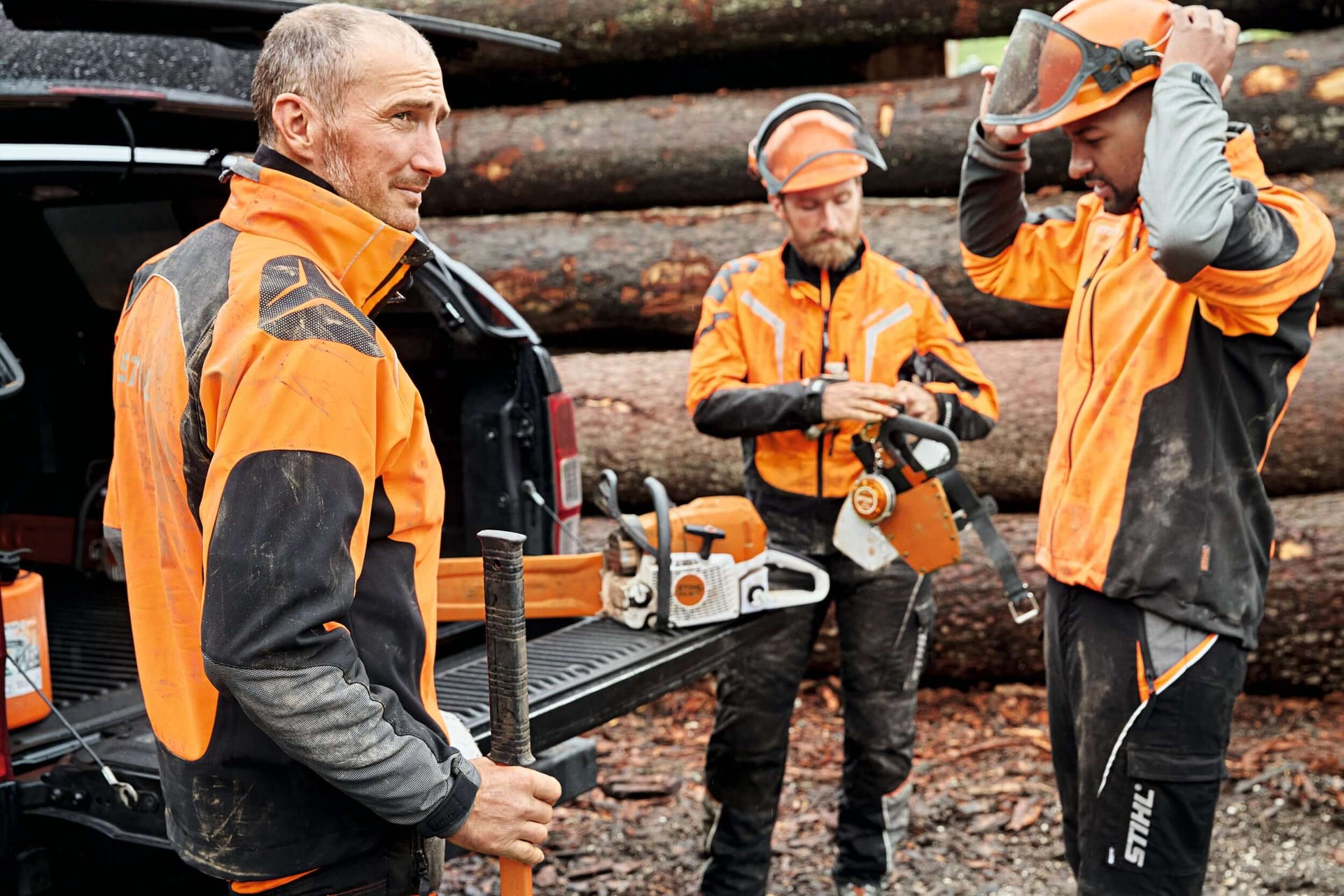 Tree surgeons preparing measuring and marking tools for forestry projects at a job site.