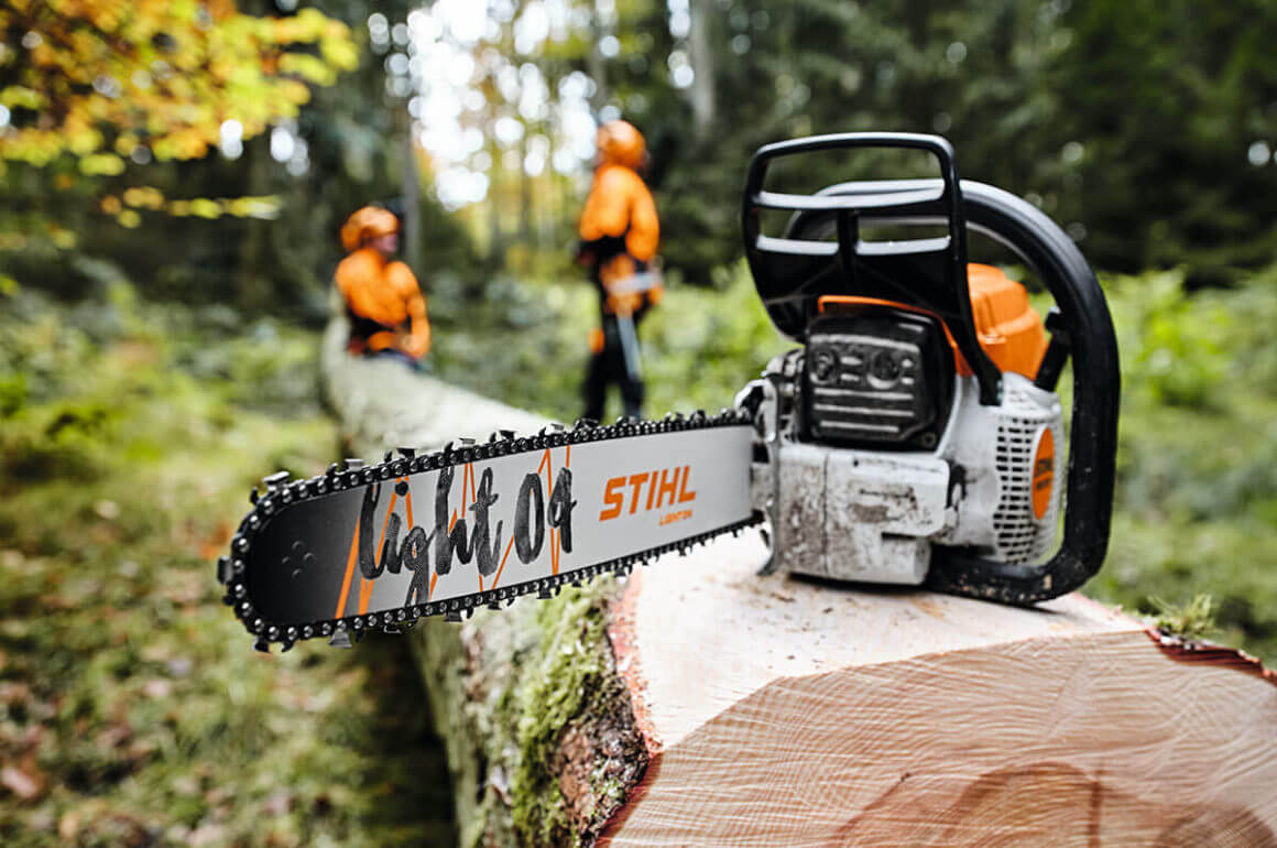 STIHL chainsaw with guide bar displayed on a fallen log, professionals working in background, ideal for tree surgeons.