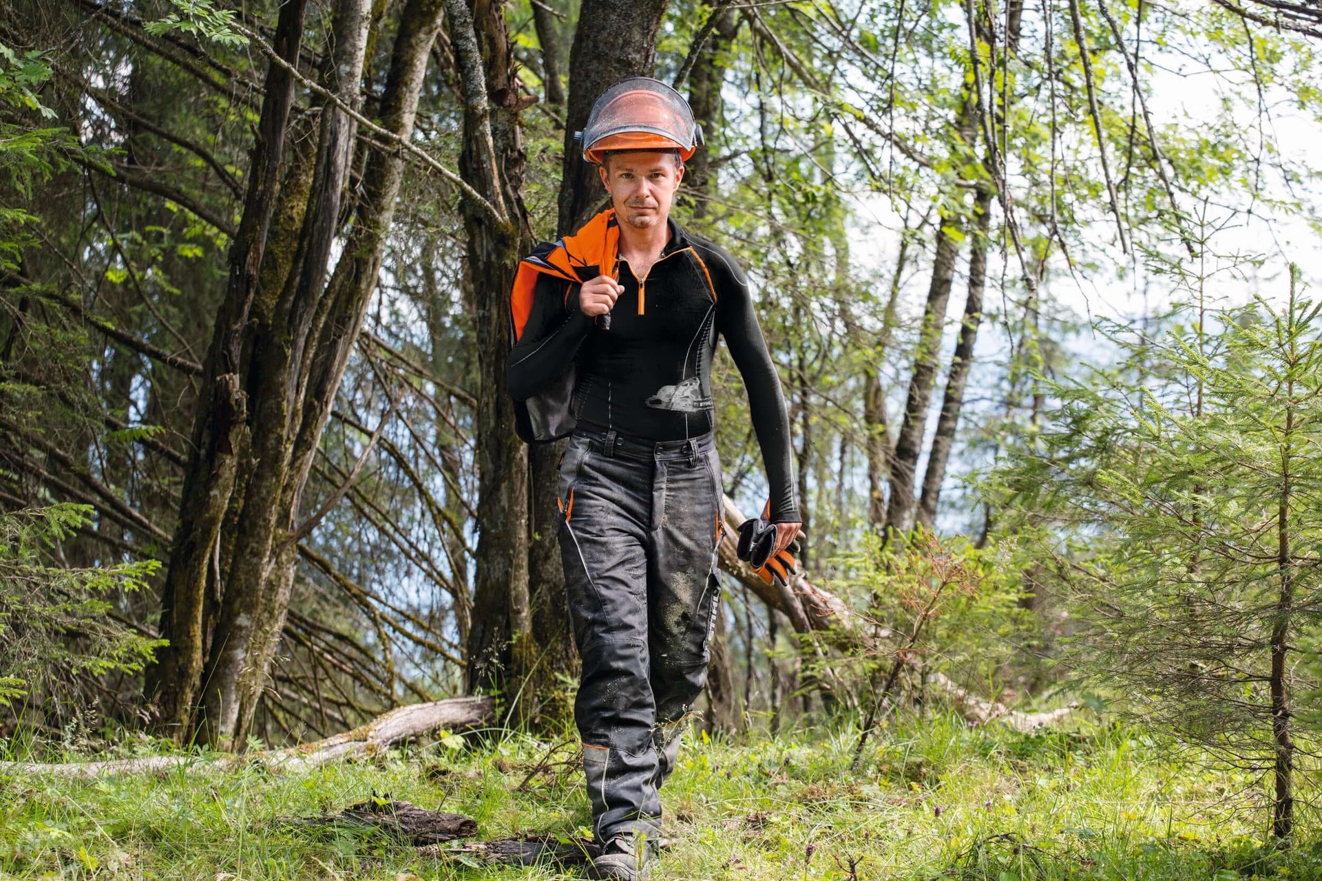 Tree surgeon in safety gear walking through the forest, highlighting functionality and comfort in workwear.
