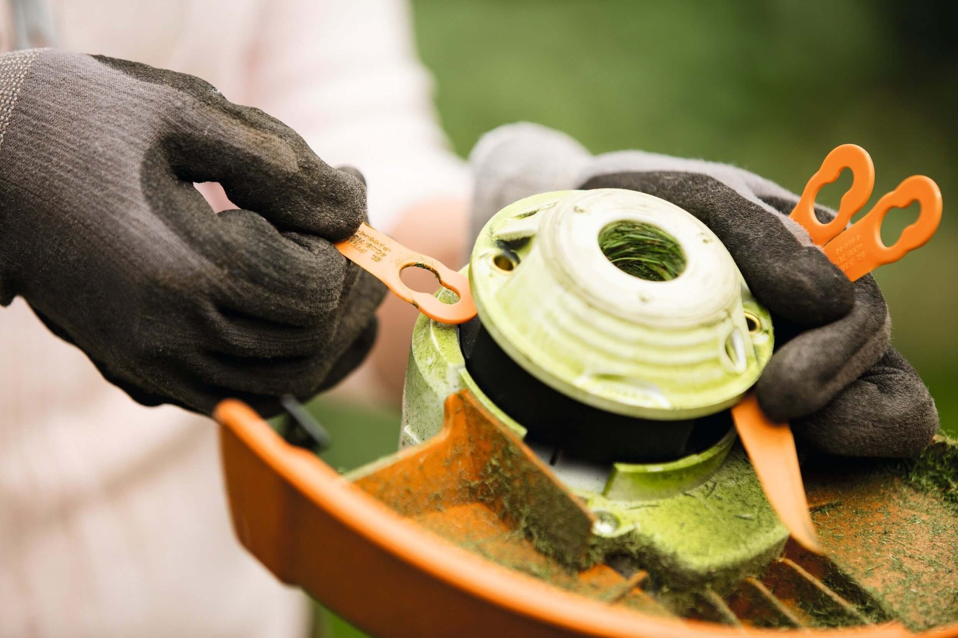 Hands wearing gloves adjusting a STIHL trimmer head with accessories for optimal garden maintenance.