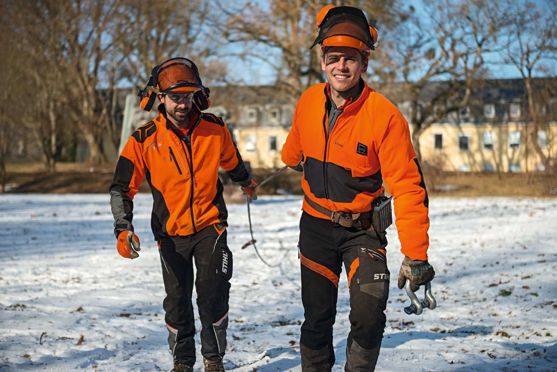 Two tree surgeons wearing STIHL clothing and PPE, ready for an arboreal task in snowy terrain.