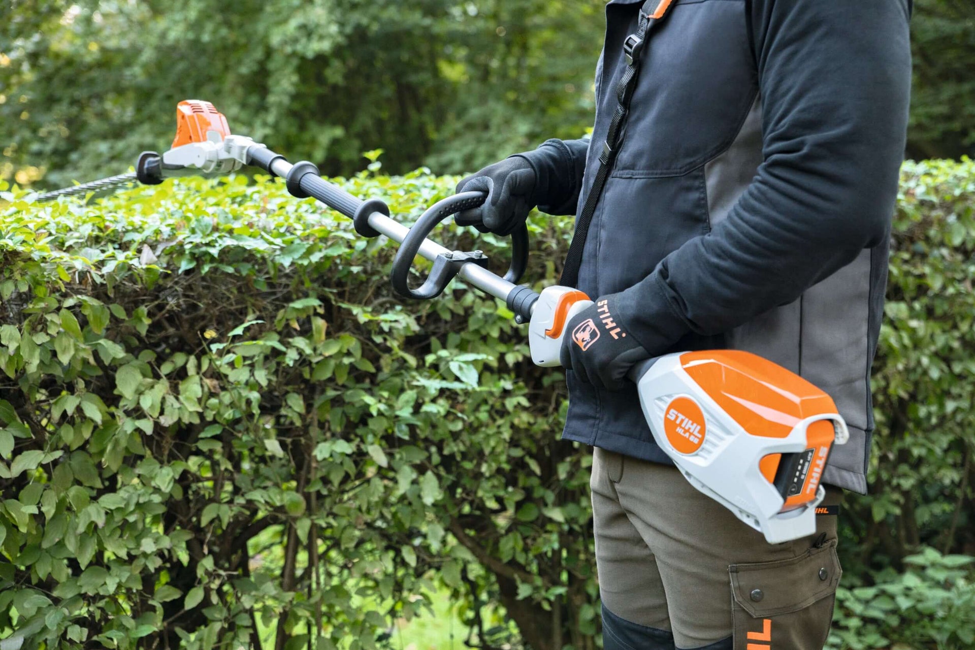Person using a STIHL hedge trimmer to maintain a well-manicured hedge, ideal for Tree Surgeons.