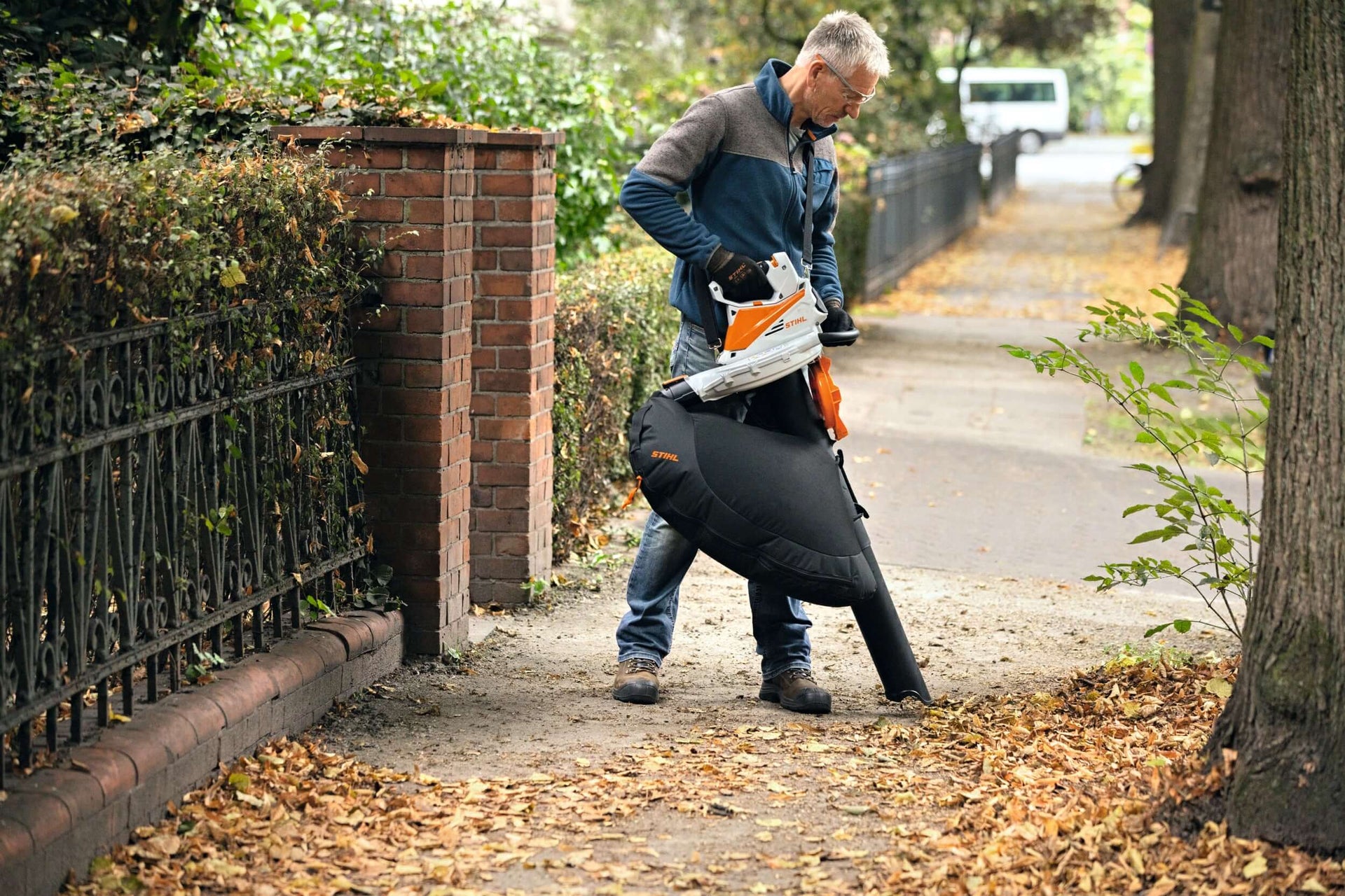 Man using a STIHL blower to clear leaves from a pathway, ideal for tree surgeons and outdoor maintenance.