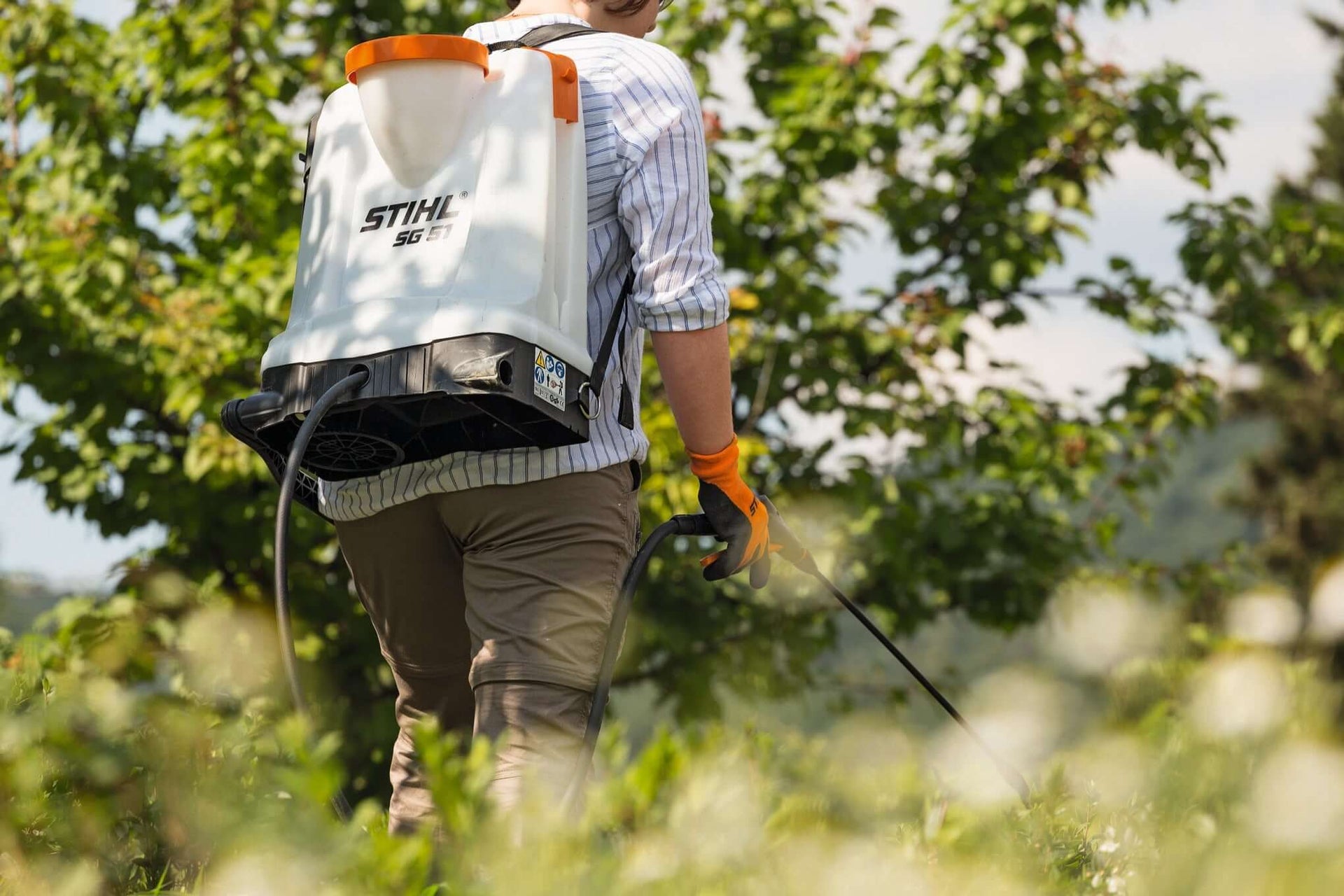 Person using a STIHL backpack sprayer in a garden, perfect for tree surgeons and pest control.