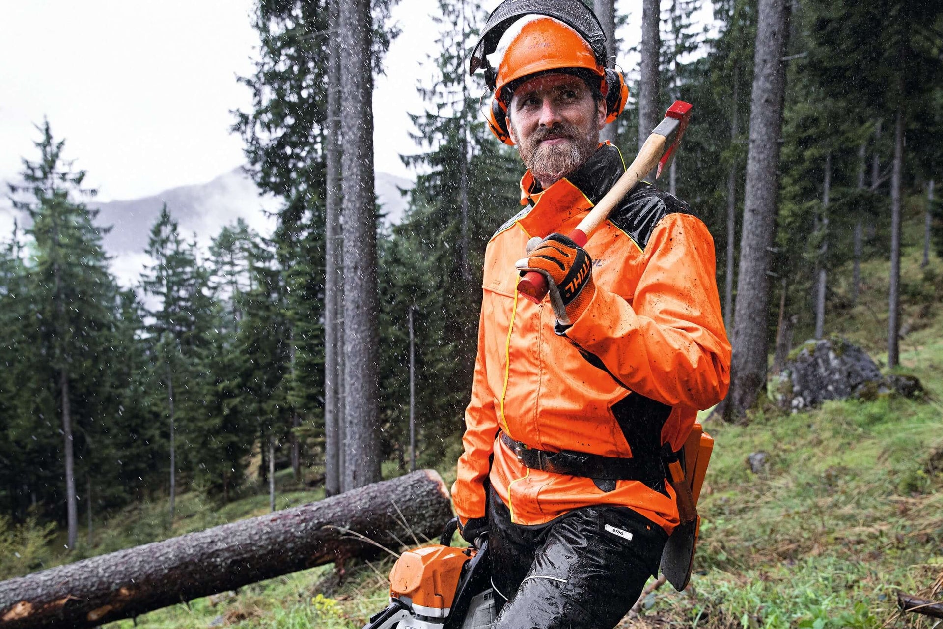 Tree surgeon in safety gear holding a tool in a forest, showcasing forestry and landscaping expertise.