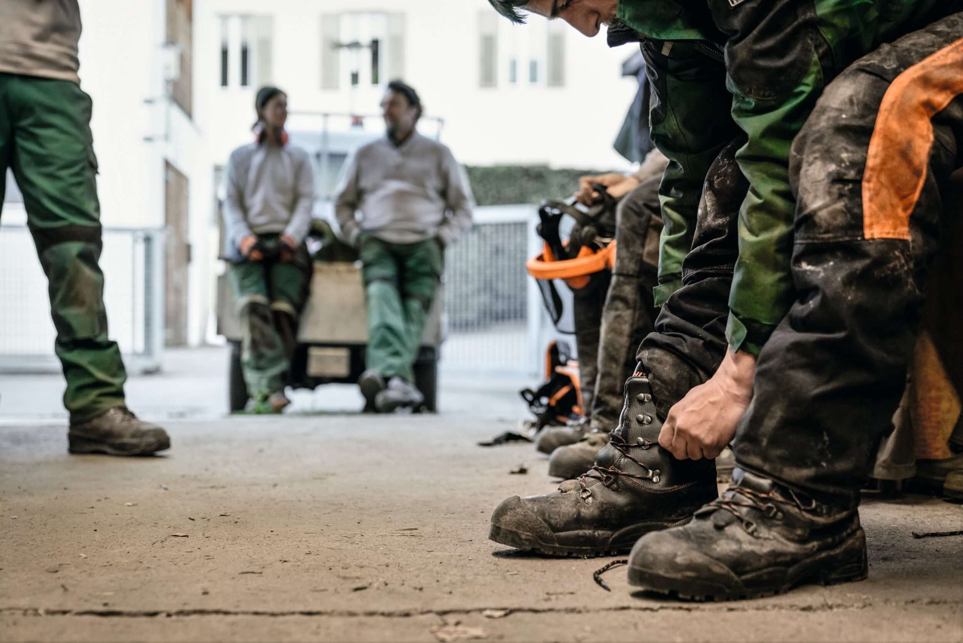 Tree surgeon preparing for work by lacing up chainsaw boots in a professional environment.