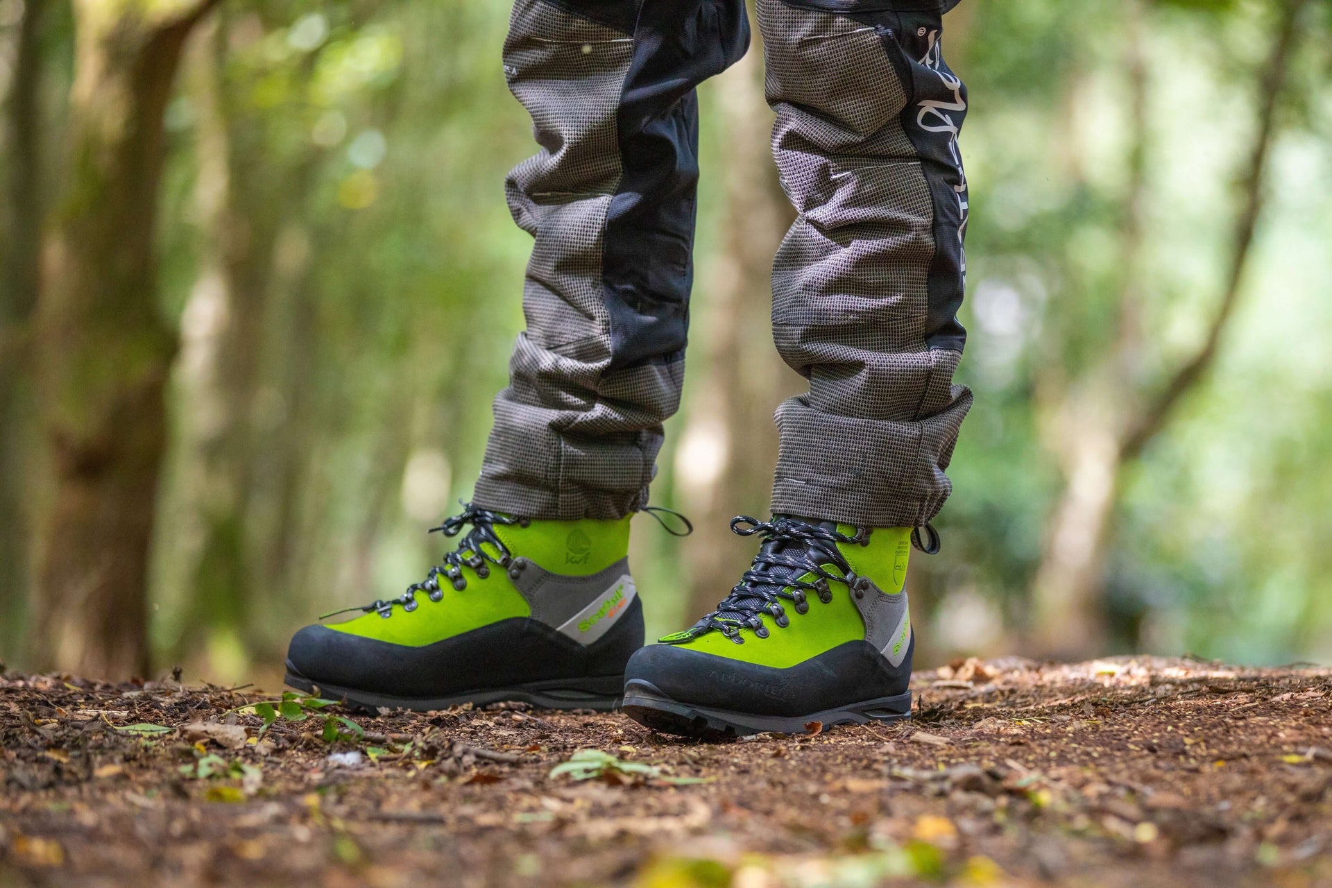 Tree surgeon wearing Arbortec chainsaw boots in a forest, designed for safety and protection during tree work.