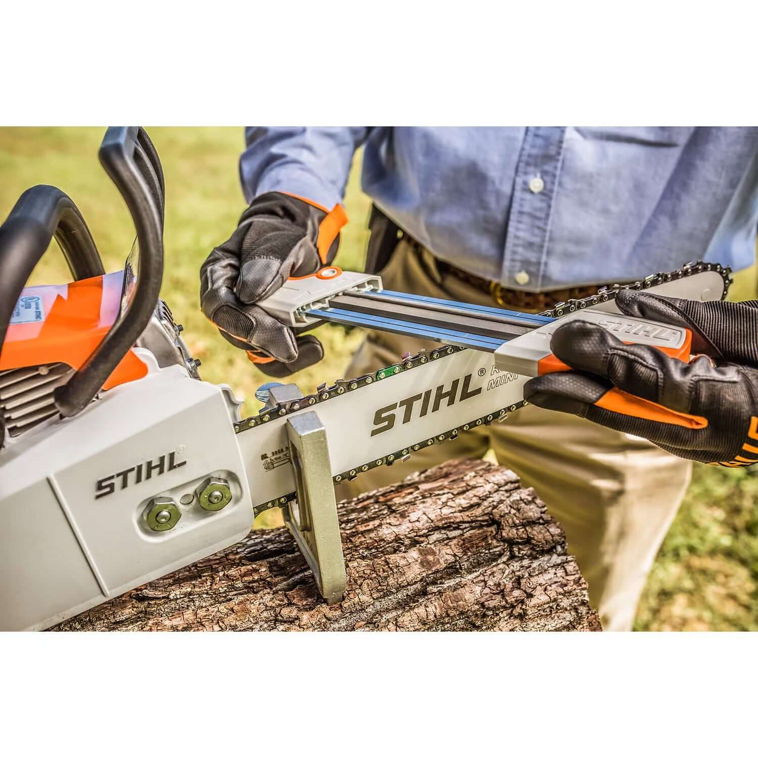 Tree surgeon using STIHL chainsaw filing kit to sharpen a chainsaw on a log for optimal cutting performance.