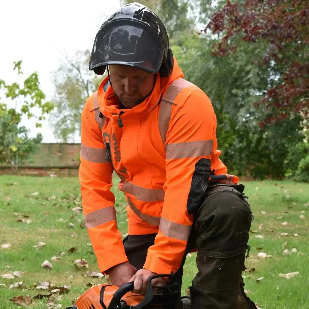 Tree surgeon in high visibility clothing, preparing equipment outdoors in a safe and conspicuous manner.