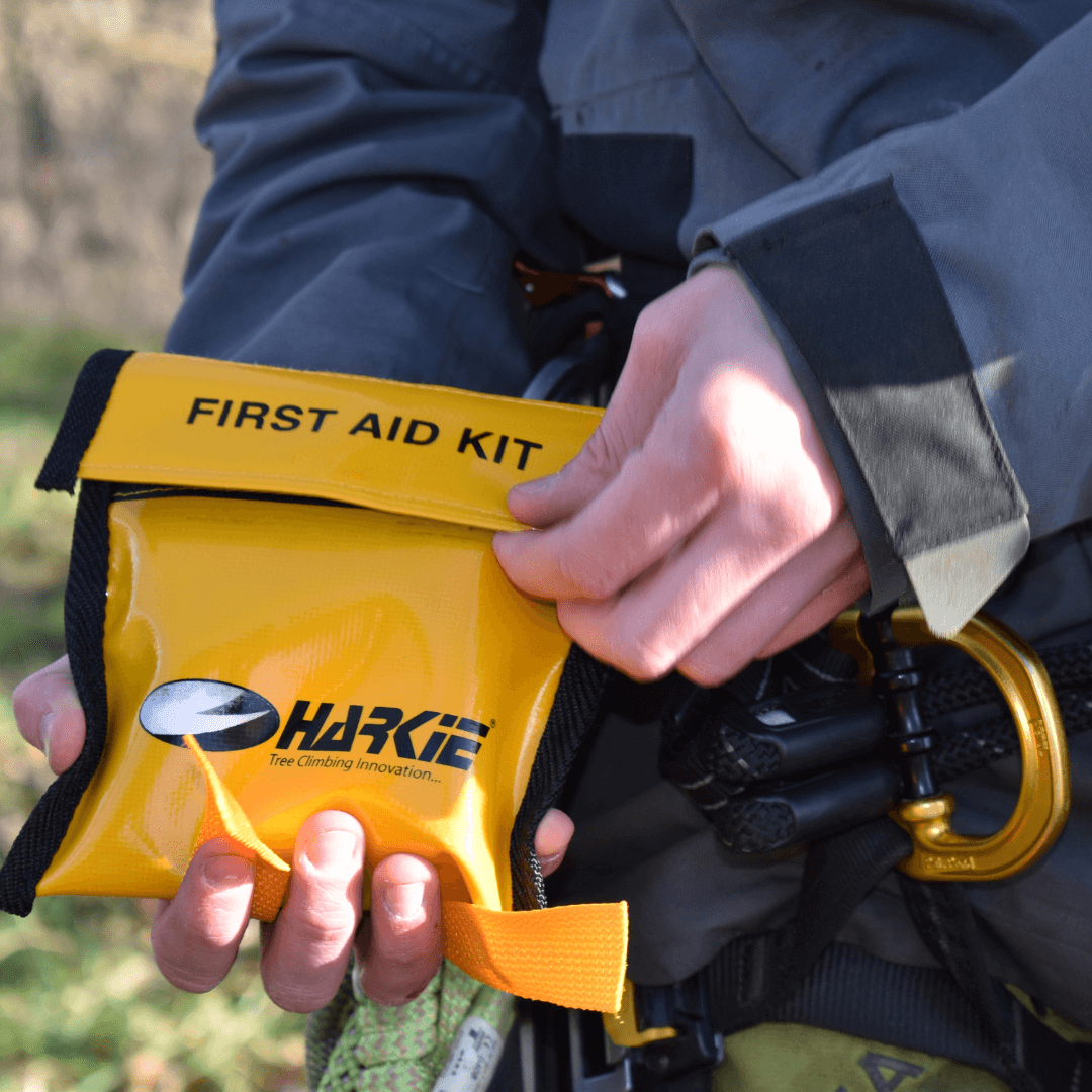 Tree surgeon holding a yellow first aid kit, essential for safety during tree work.