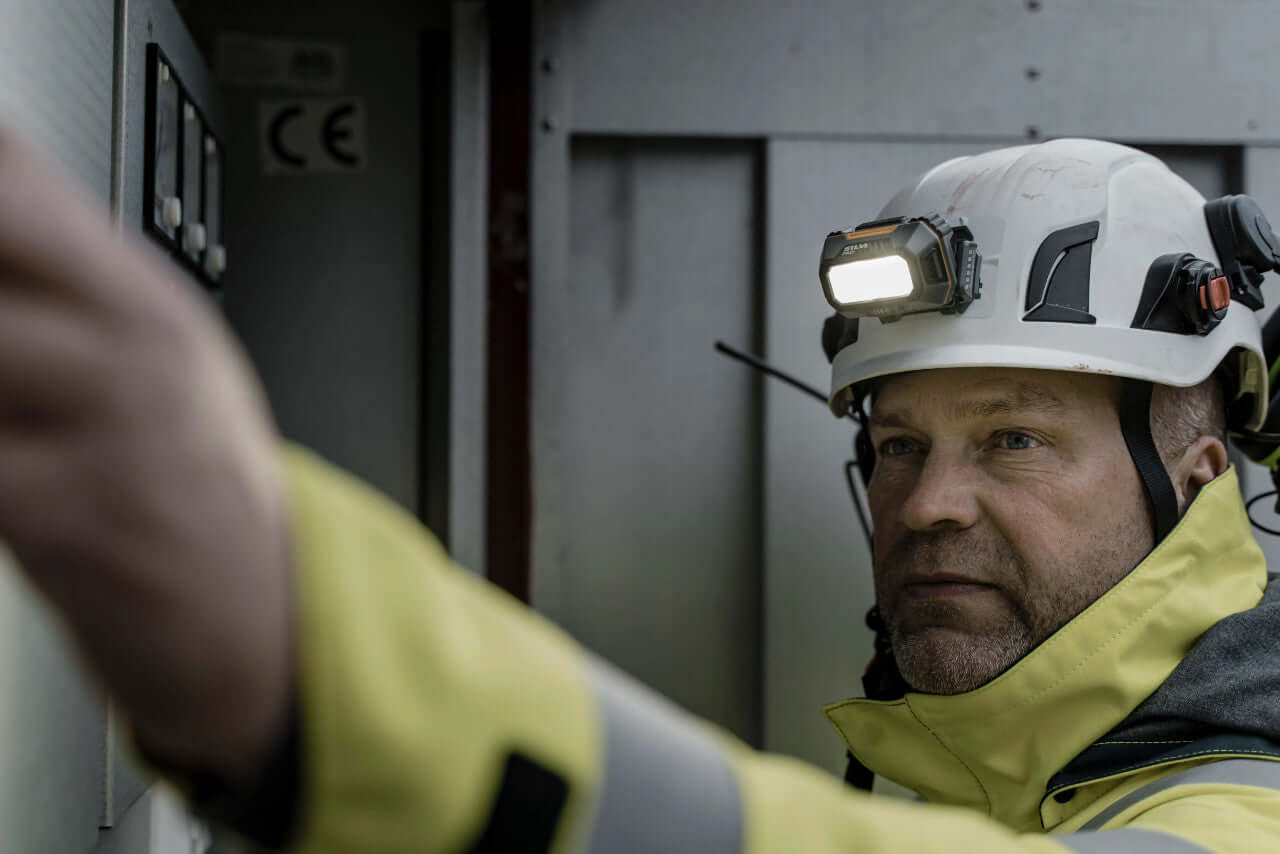 Worker using a Silva head torch while operating machinery, ideal for tree surgeons and outdoor tasks.