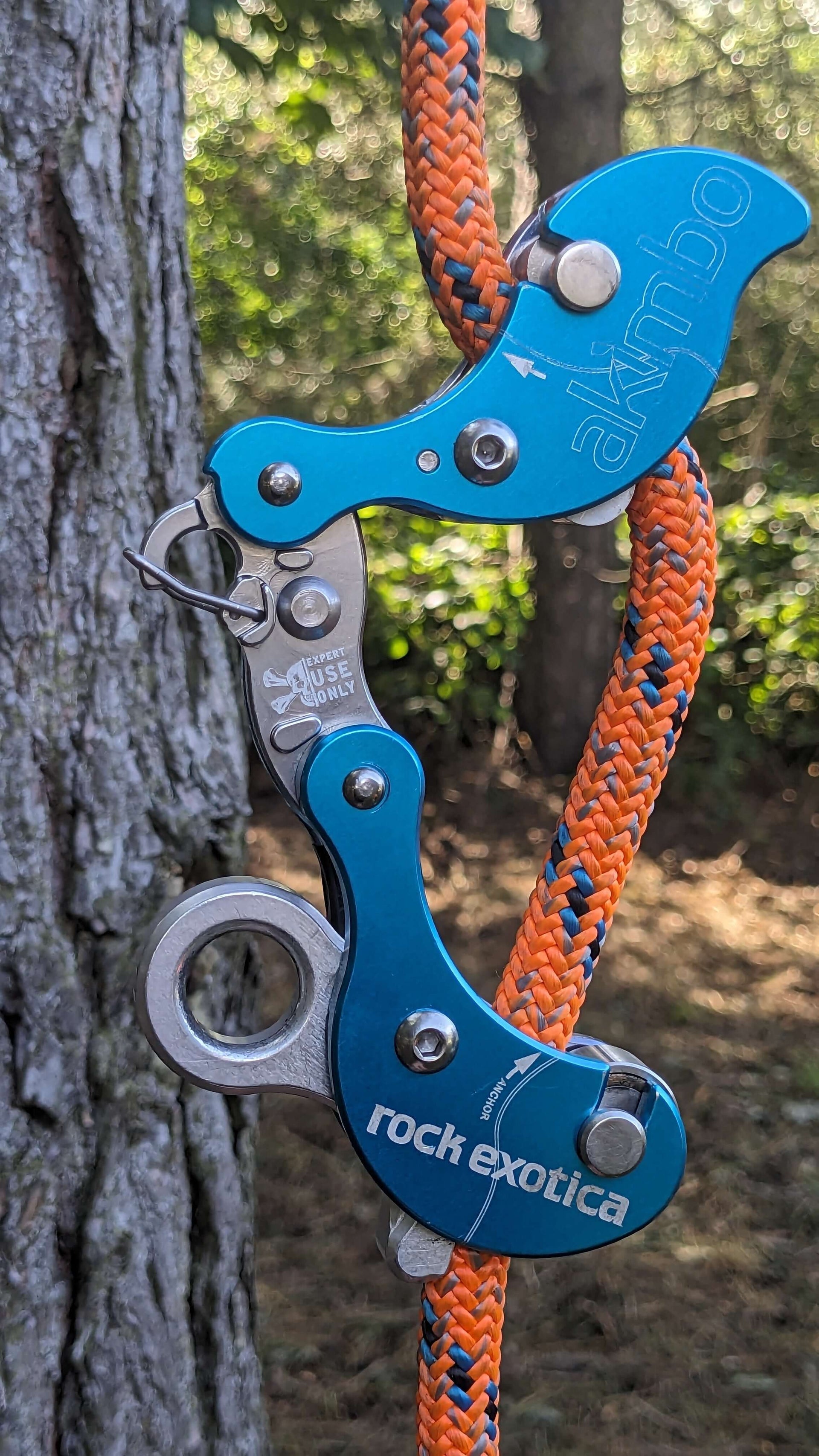 A blue Akimbo climbing device by Rock Exotica, secured on orange rope, ideal for tree surgeons and rigging.