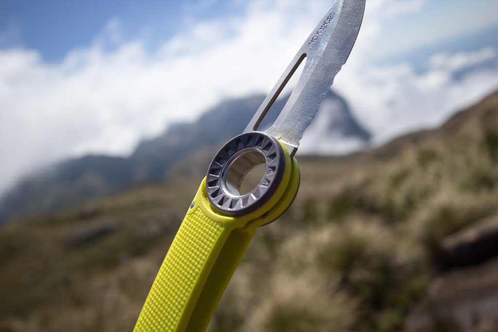 Petzl Spatha Rescue Knife with a sharp blade, ideal for tree surgeons, set against a scenic mountainous background.
