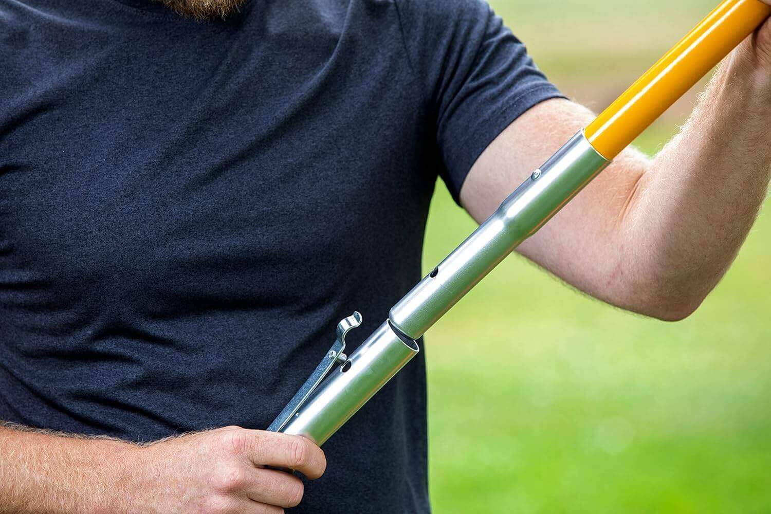 Close-up of a person using a STEIN pole saw attachment, showcasing the adaptor mechanism for tree pruning.