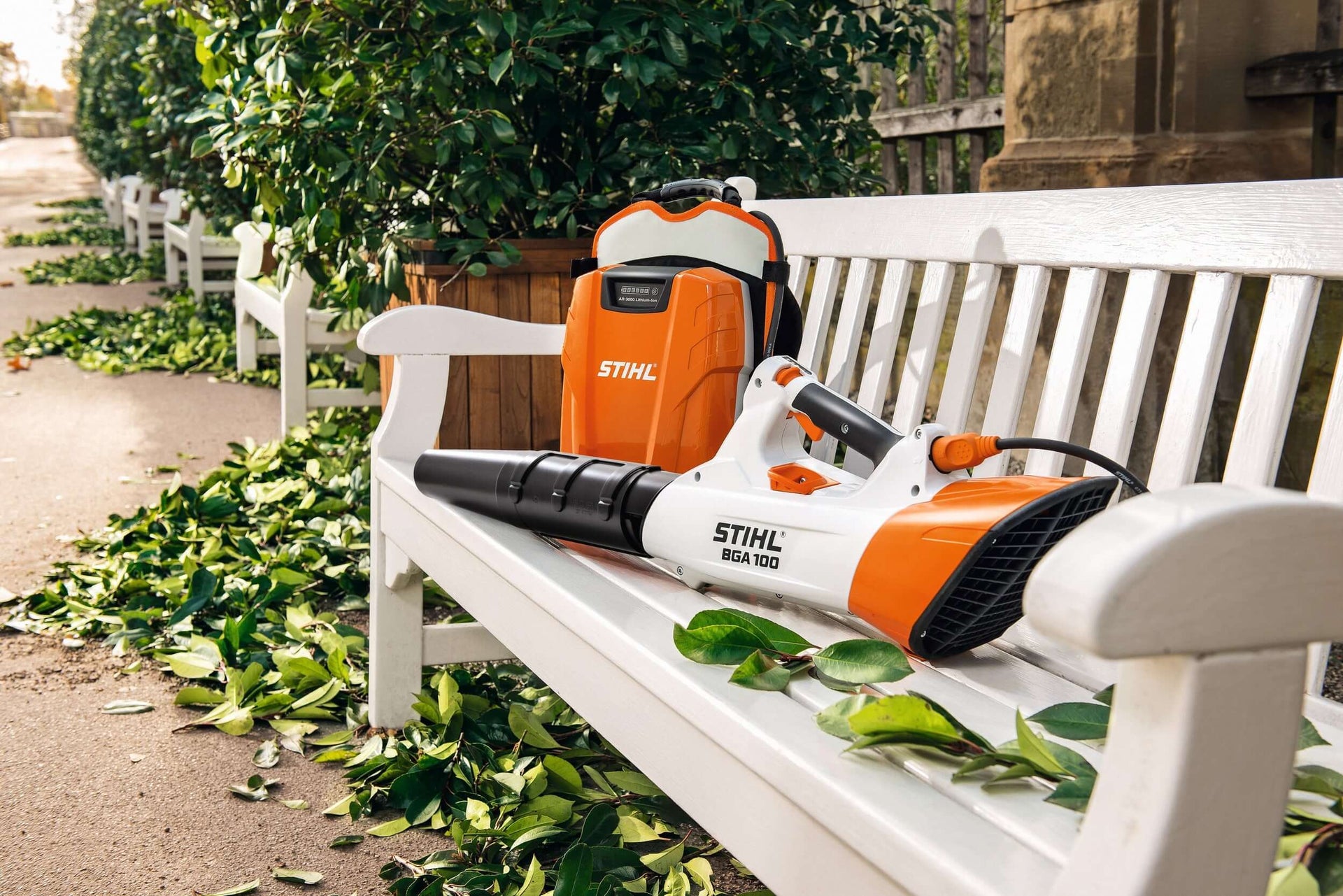 STIHL BGA 100 battery blower on a bench surrounded by leaves, ideal for tree surgeons and outdoor cleaning.