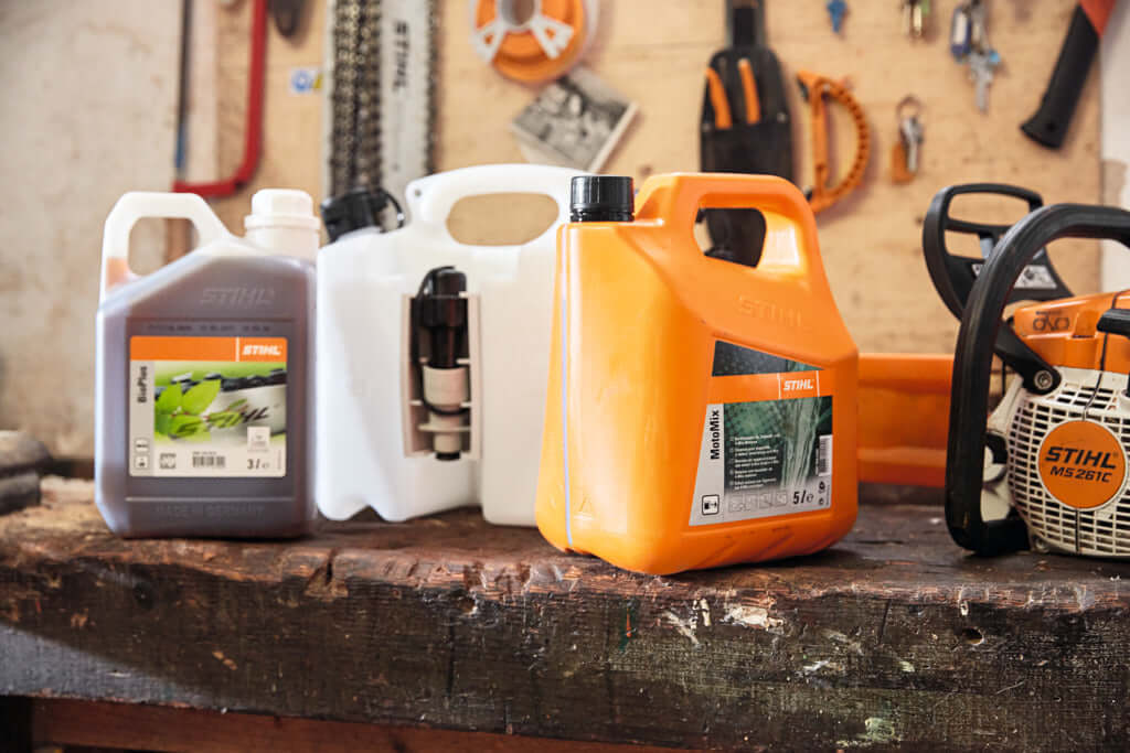 STIHL fuel combination cans in various colors on a workbench, essential for tree surgeons and outdoor equipment.