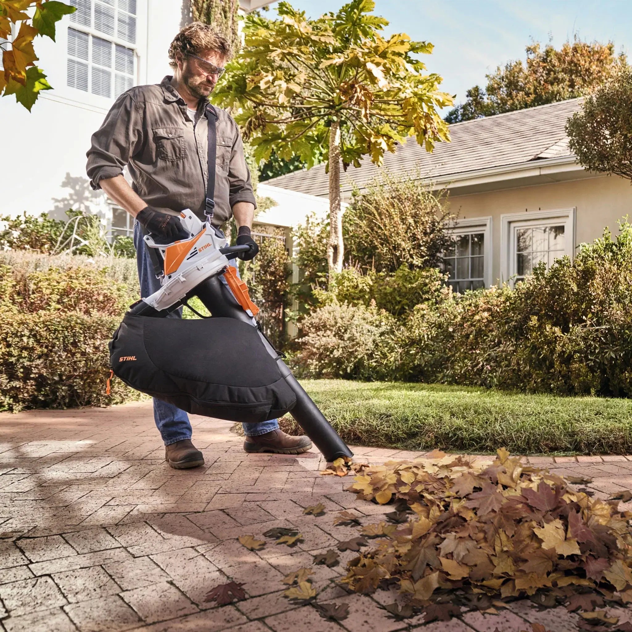 User using a STIHL leaf blower vacuum to clear leaves from a patio, perfect for any Tree Surgeon.