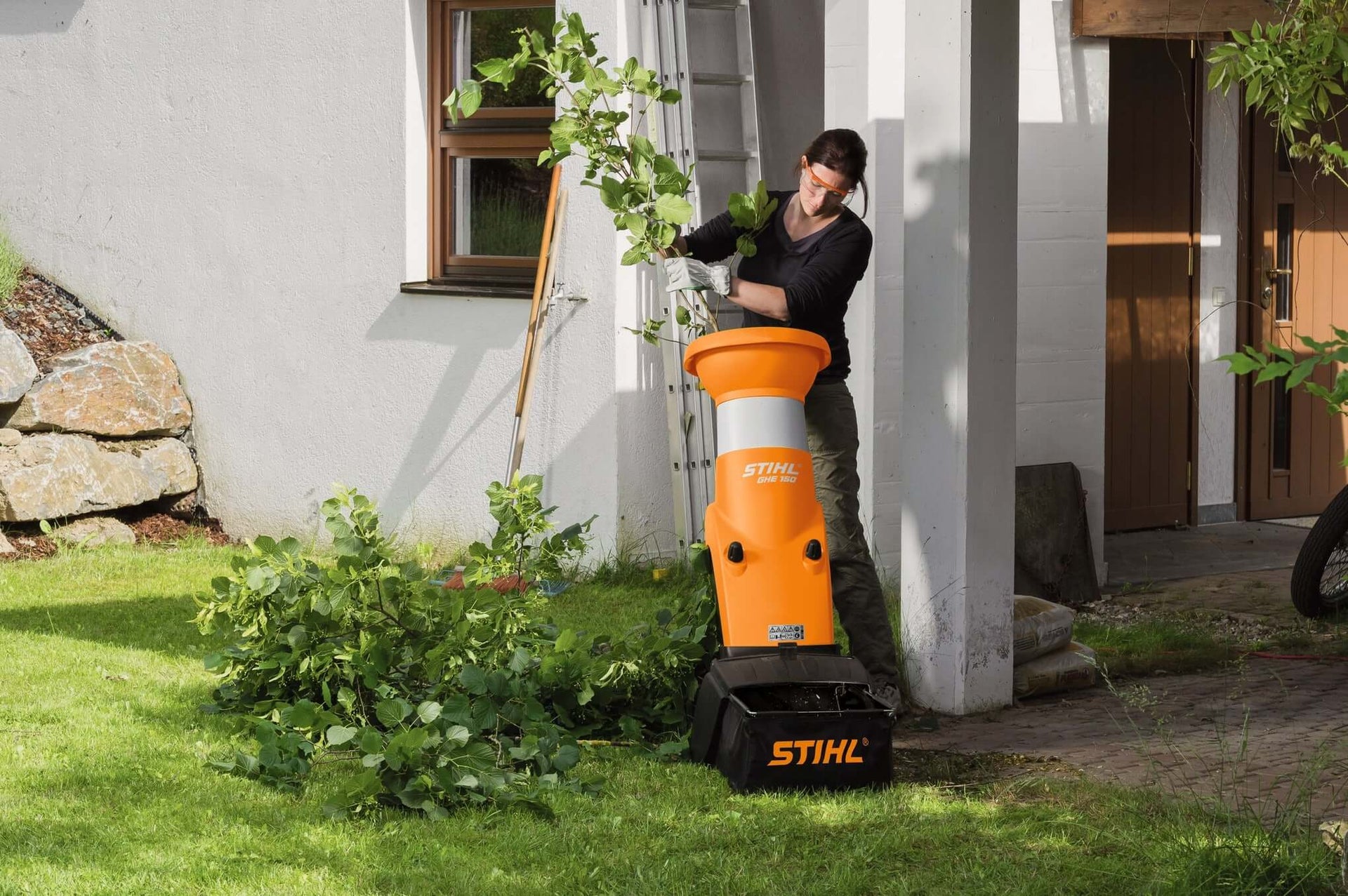 Person using a STIHL shredder in a garden, managing branches and garden waste efficiently.