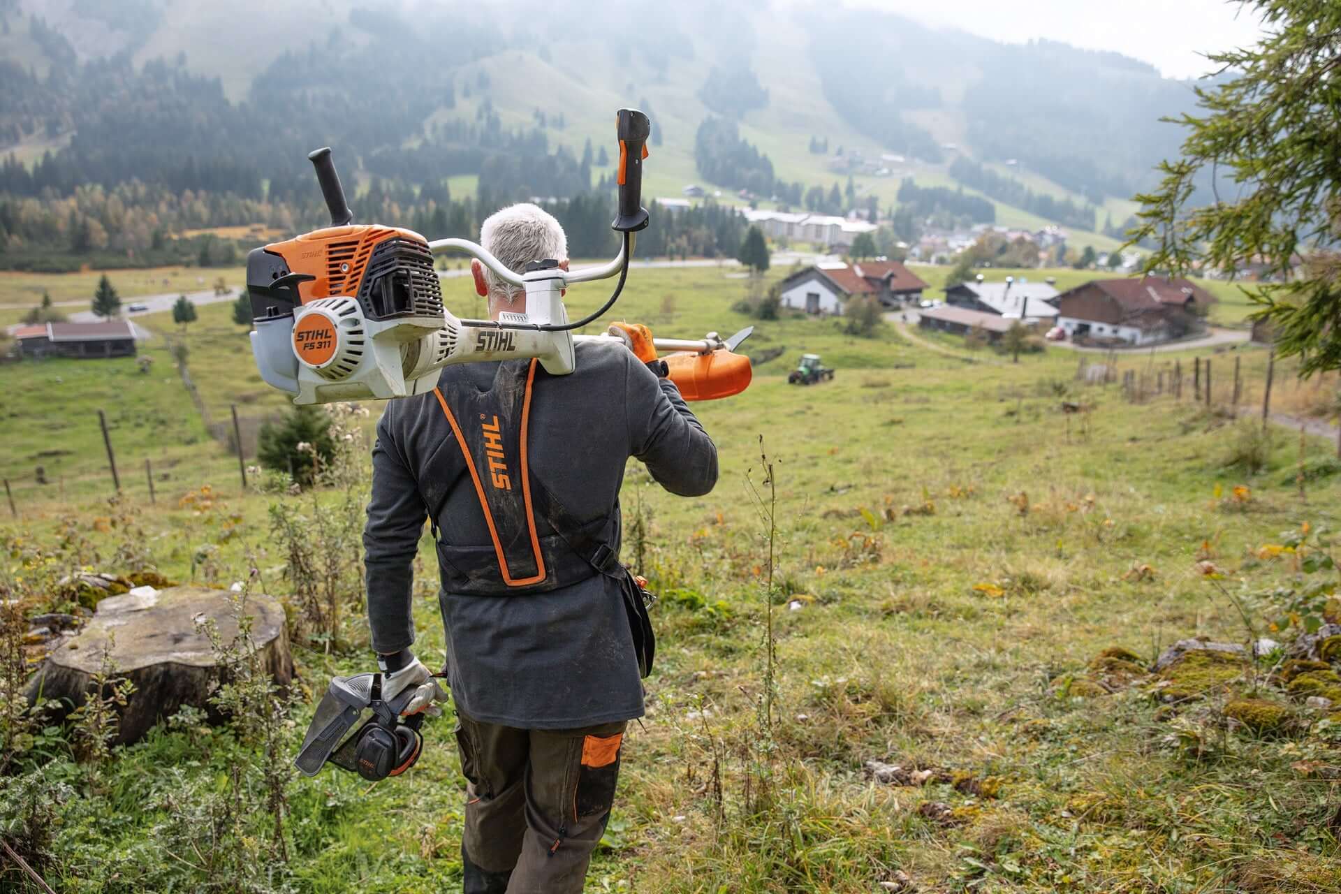 Tree surgeon using STIHL brushcutter on a hillside, showcasing landscape maintenance capabilities.