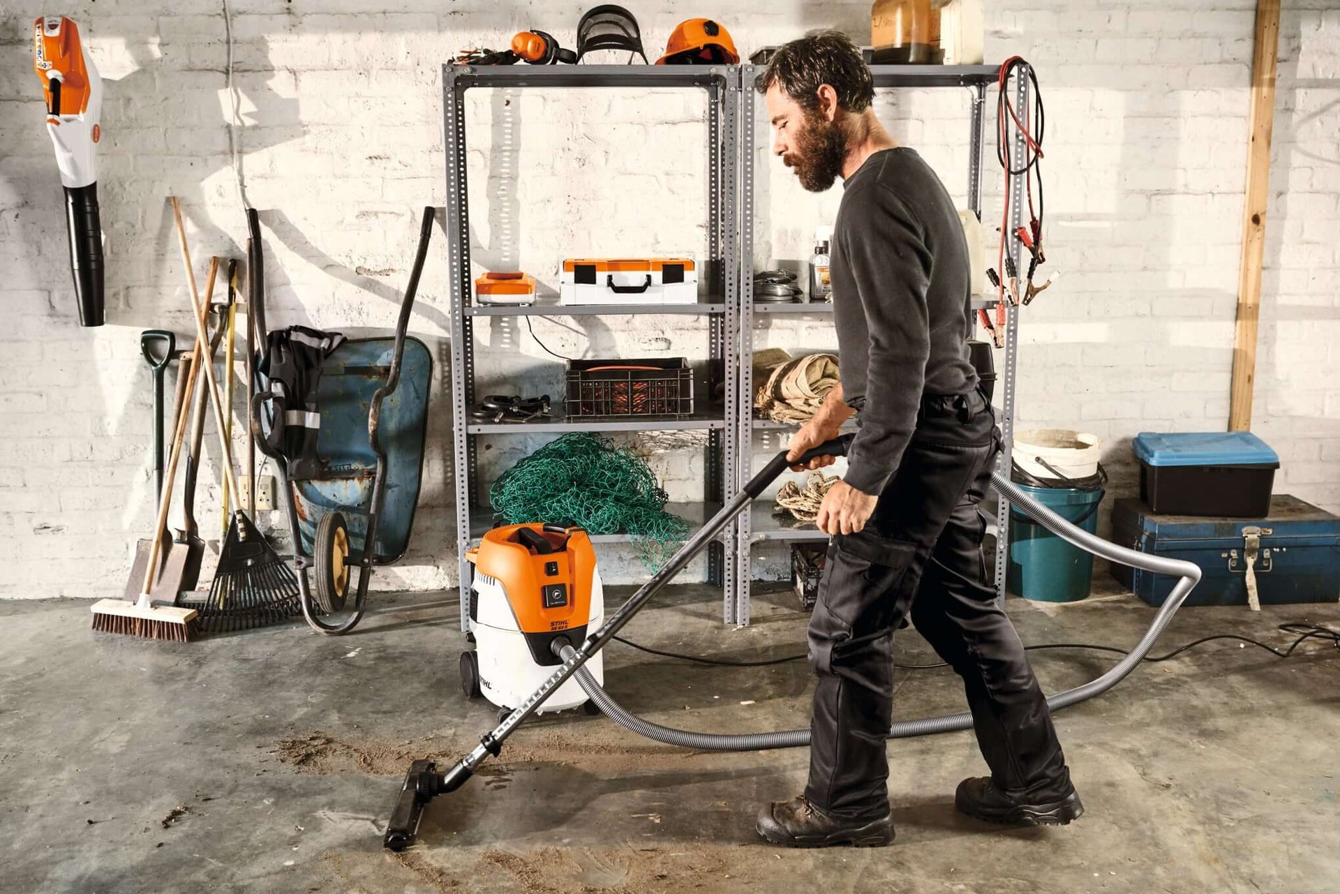 Man using STIHL vacuum in a garage, demonstrating efficient cleaning with vacuum accessories.