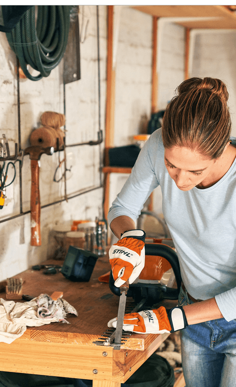 Woman using STIHL sharpening tools for maintenance in a workshop, ensuring top performance for her equipment.