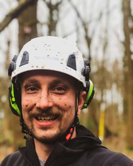 Tree Surgeon wearing a SOVOS chainsaw climbing helmet in a wooded area, smiling and ready for work.