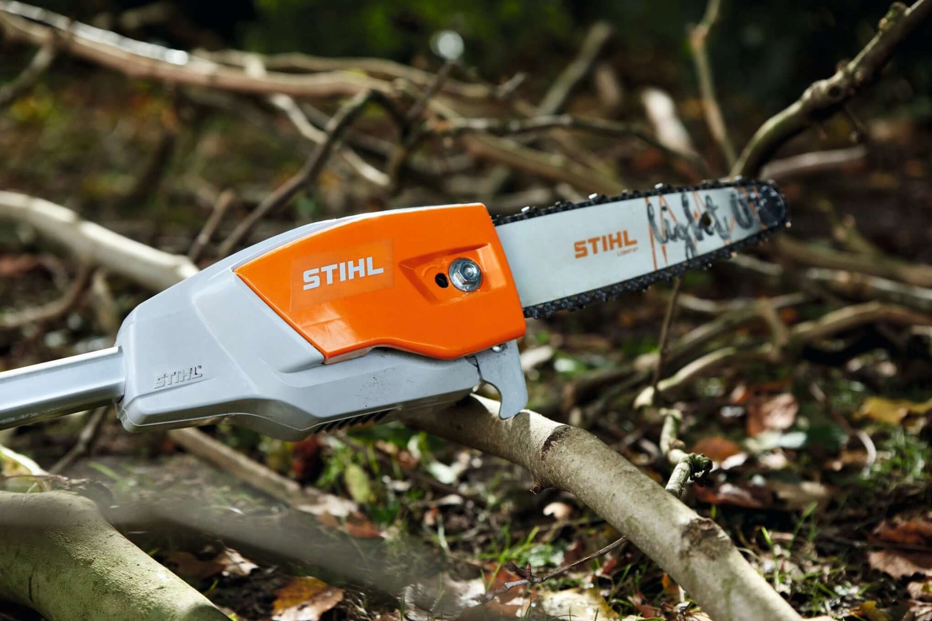 STIHL pole pruner chainsaw resting on branches, ideal for tree surgeons and precision pruning tasks.