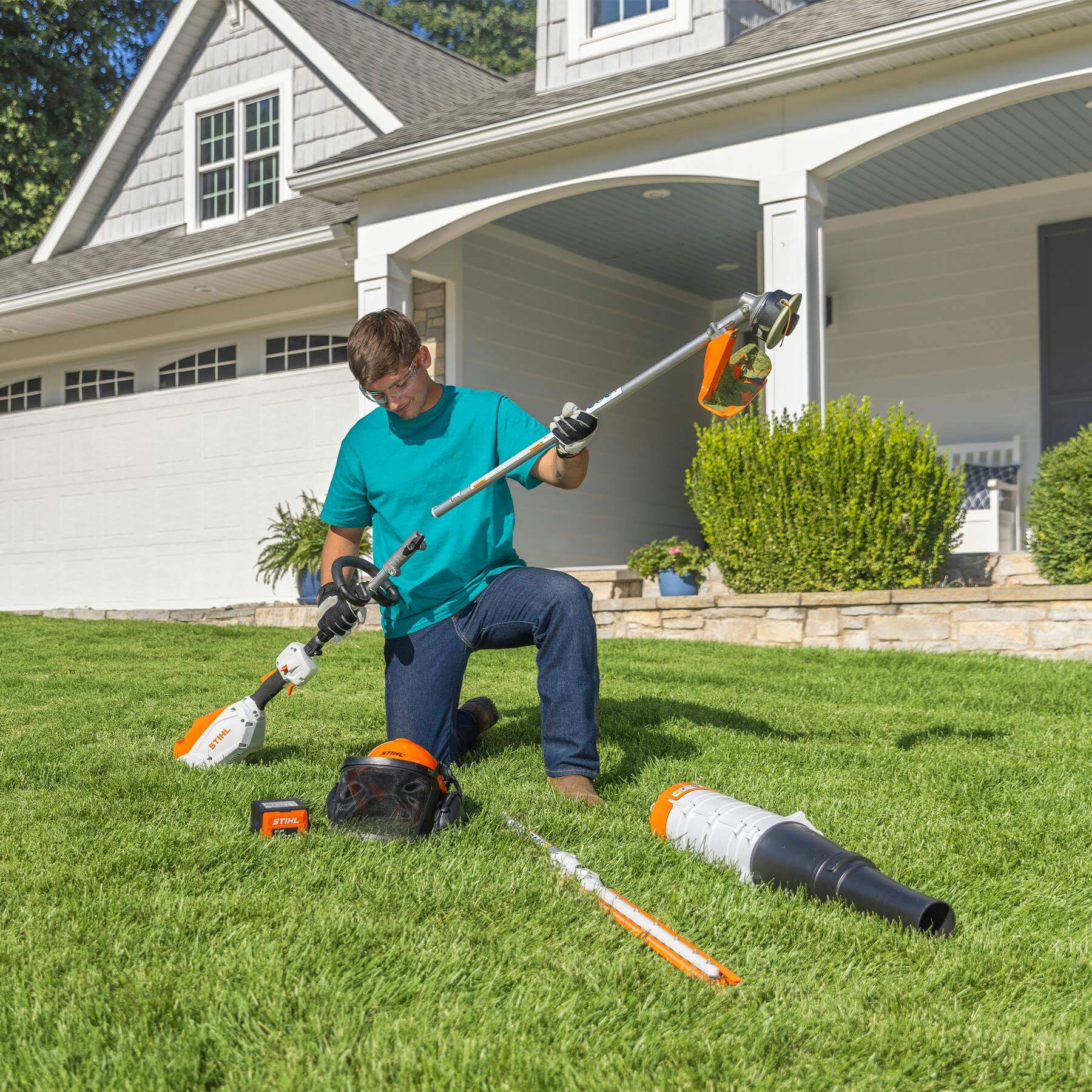Man using STIHL strimmer attachments for versatile landscaping in a well-kept lawn outside a home.