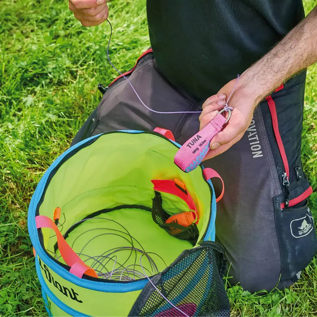 Tree surgeon organizing throwline in a colorful storage bag for efficient workflow and tangle-free use.
