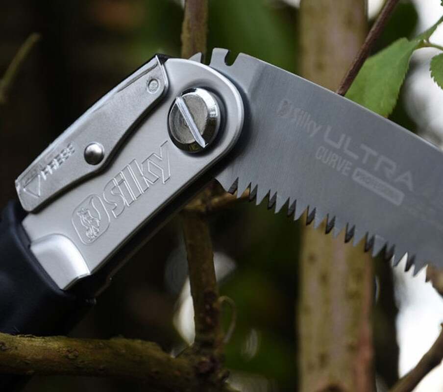 Close-up of a Silky folding hand saw blade, ideal for tree surgeons, showcasing its sharp curve and ergonomic design.