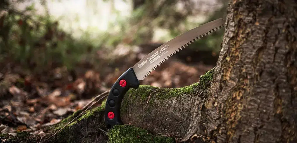 Straight hand saw resting against a tree trunk, ideal for tree surgeons and gardening enthusiasts.