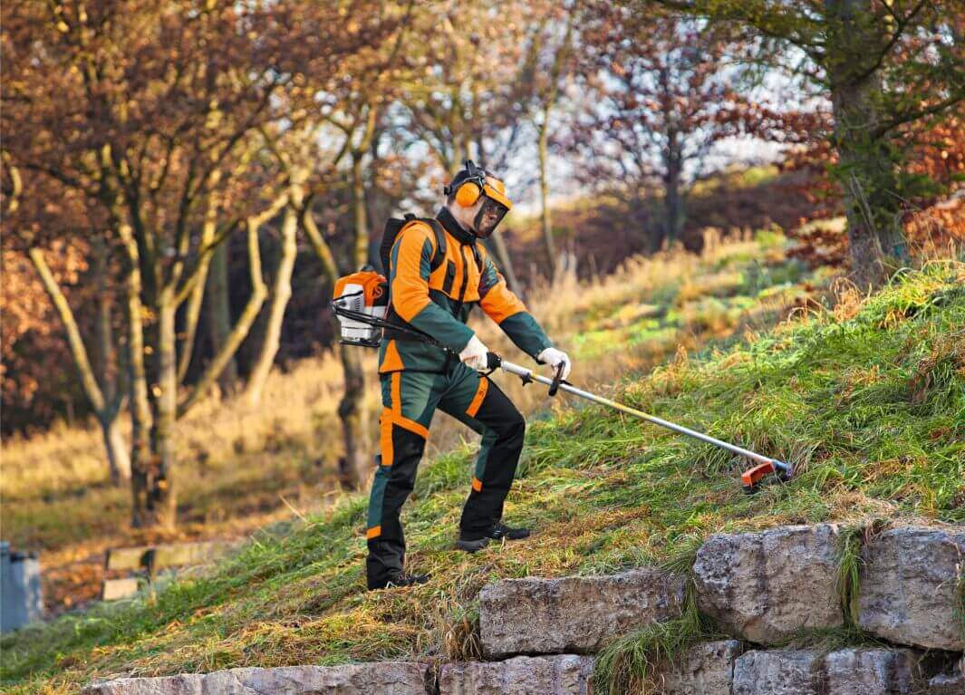 Professional using STIHL Backpack Brush Cutters for effective vegetation control on steep terrain.