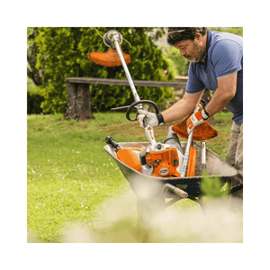 Man using KM 56 RC-E Petrol KombiEngine in a wheelbarrow for garden maintenance.