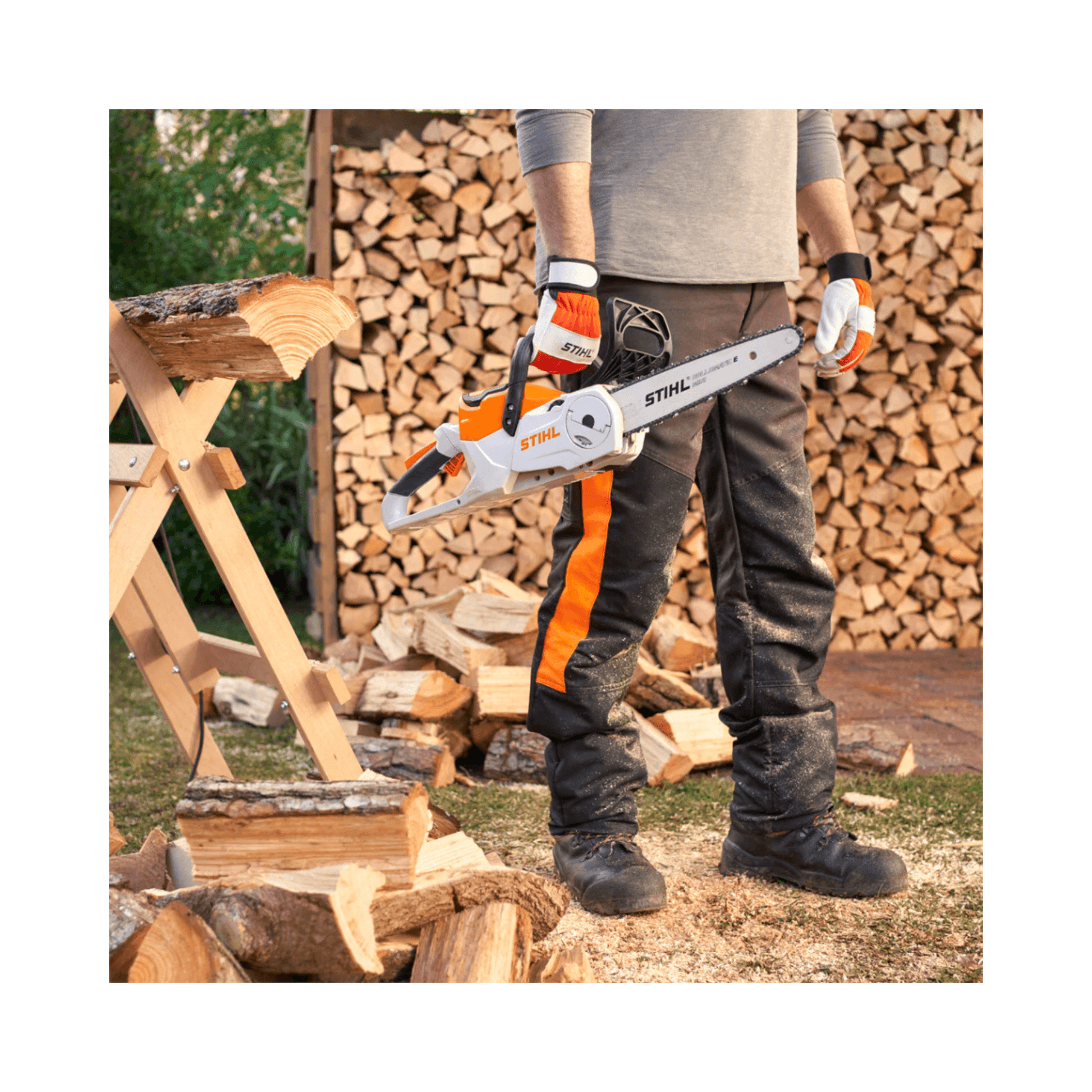 MSA 60 C-B Cordless Chainsaw 12" held by a person in protective gear near stacked firewood.