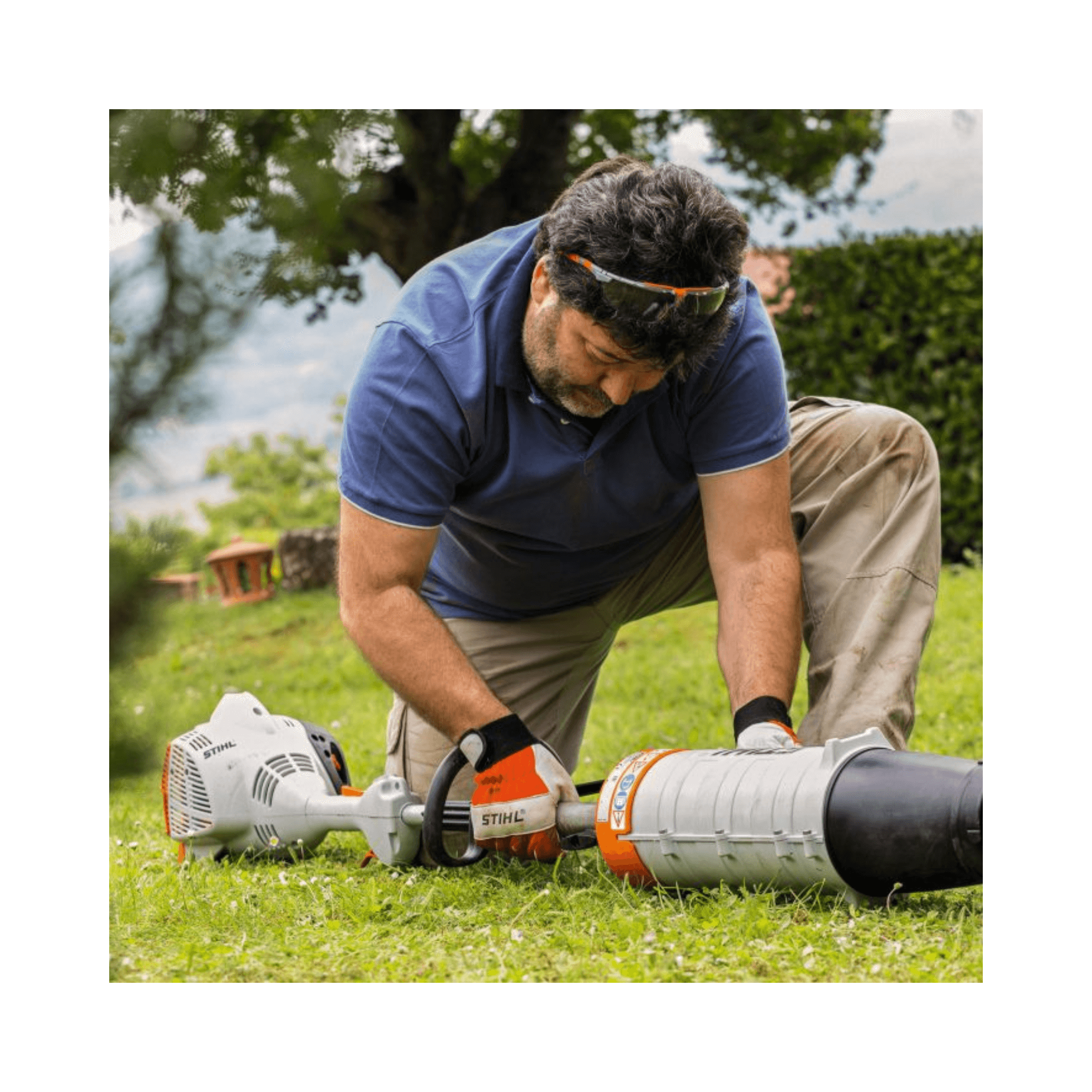 Man using STIHL KM 56 RC-E Petrol KombiEngine for garden maintenance on a sunny day.