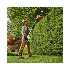 Person using HLA 40 Cordless Telescopic Long-Reach Hedge Trimmer for precise trimming, preferred by tree surgeons and arborists.