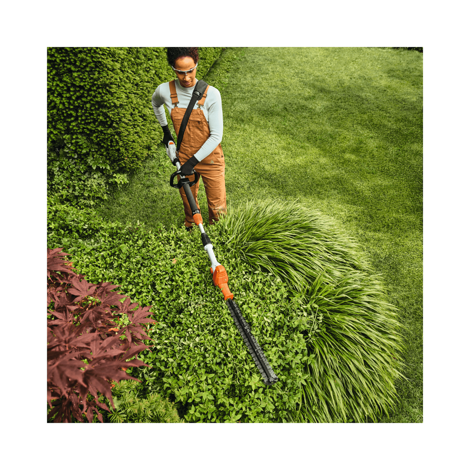 User using the HLA 40 Cordless Telescopic Long-Reach Hedge Trimmer for precise garden trimming.