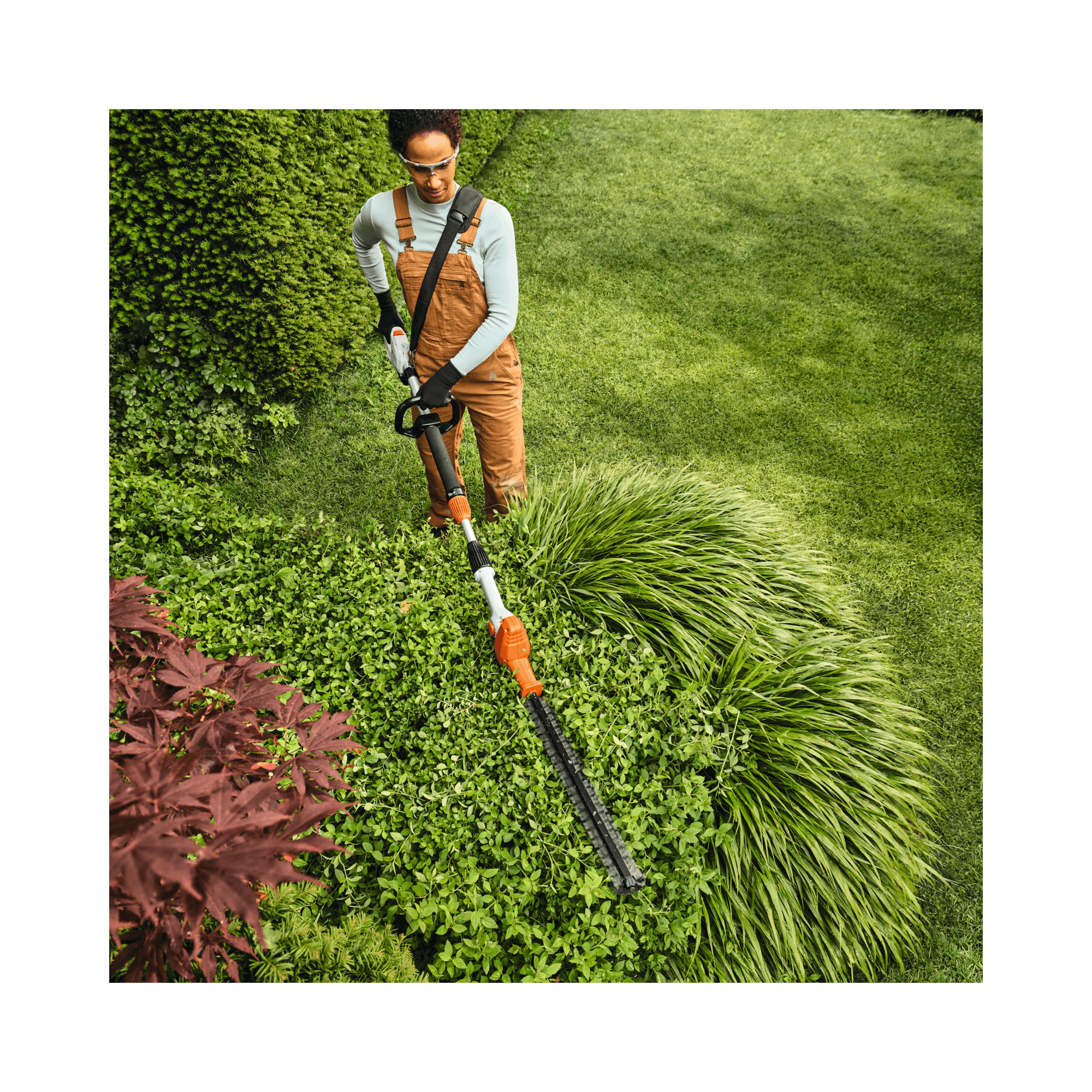 User using the HLA 40 Cordless Telescopic Long-Reach Hedge Trimmer for precise garden trimming.