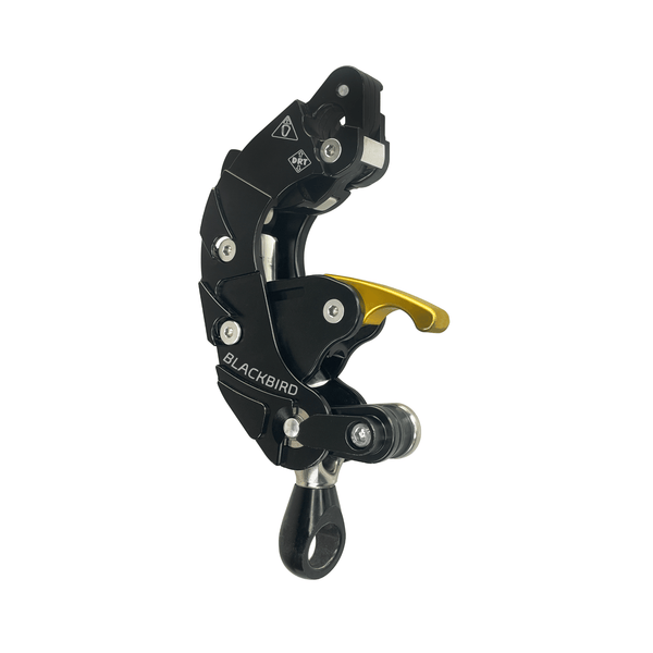 ART BlackBird mechanical rope ascender/descender, side view. Compact, dark metal device for tree climbing. Features rope channels, cam, and attachment points for single or double rope systems.