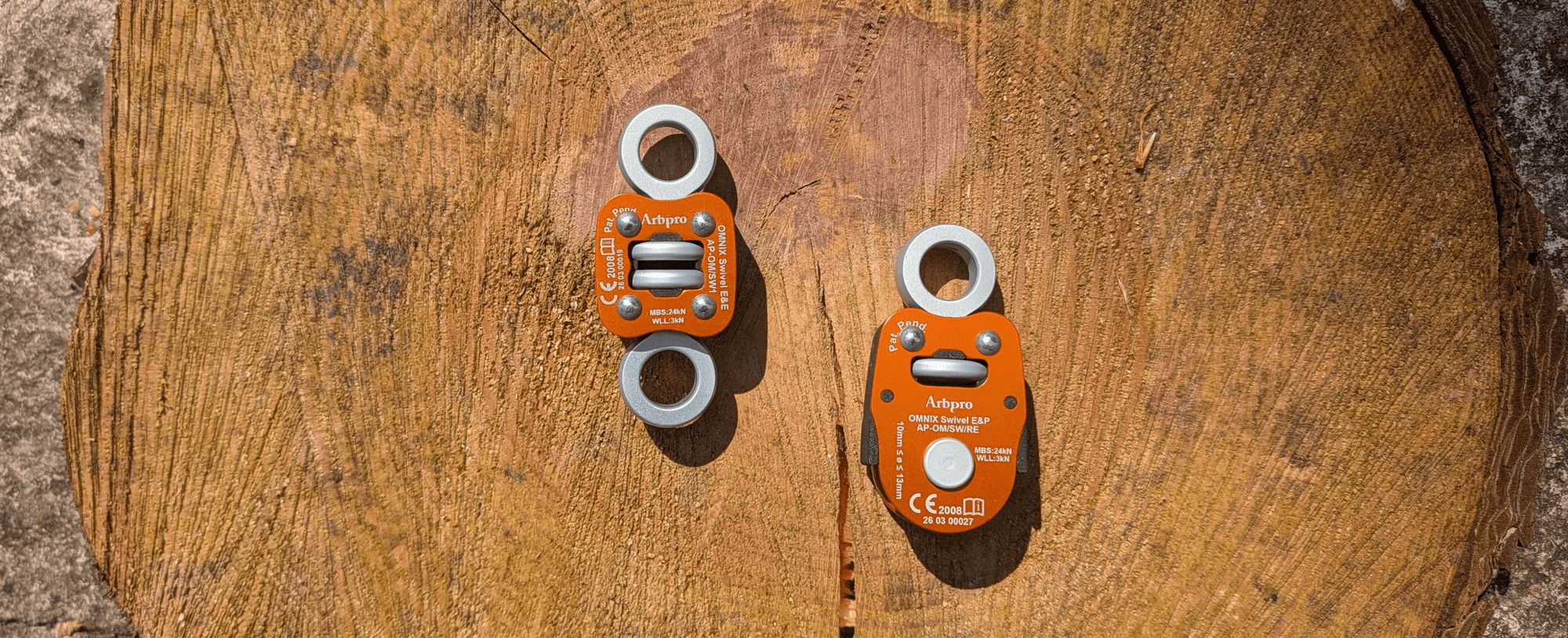 Two orange climbing pulleys placed on a wooden surface, showcasing their design and features.