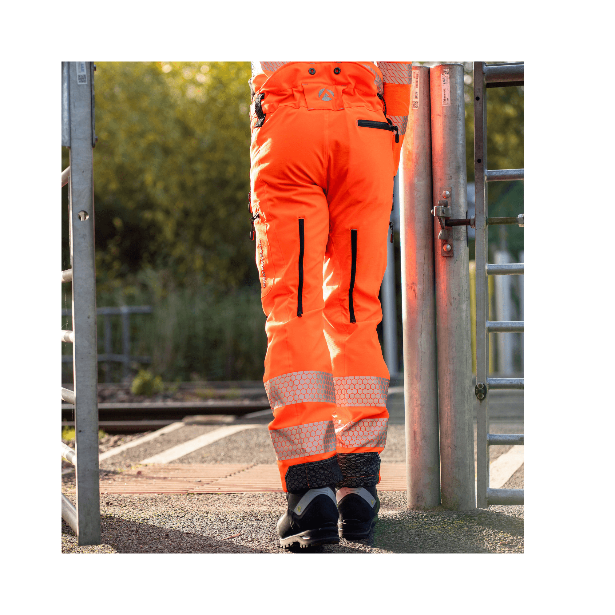 Breatheflex Pro Rail Spec Trousers Design Type C Class 2 Hi Viz Orange on a person at a rail crossing.