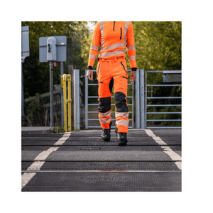 Breatheflex Pro Rail Spec Trousers Design Type C Class 2 Hi Viz Orange worn by a worker on a railway crossing.
