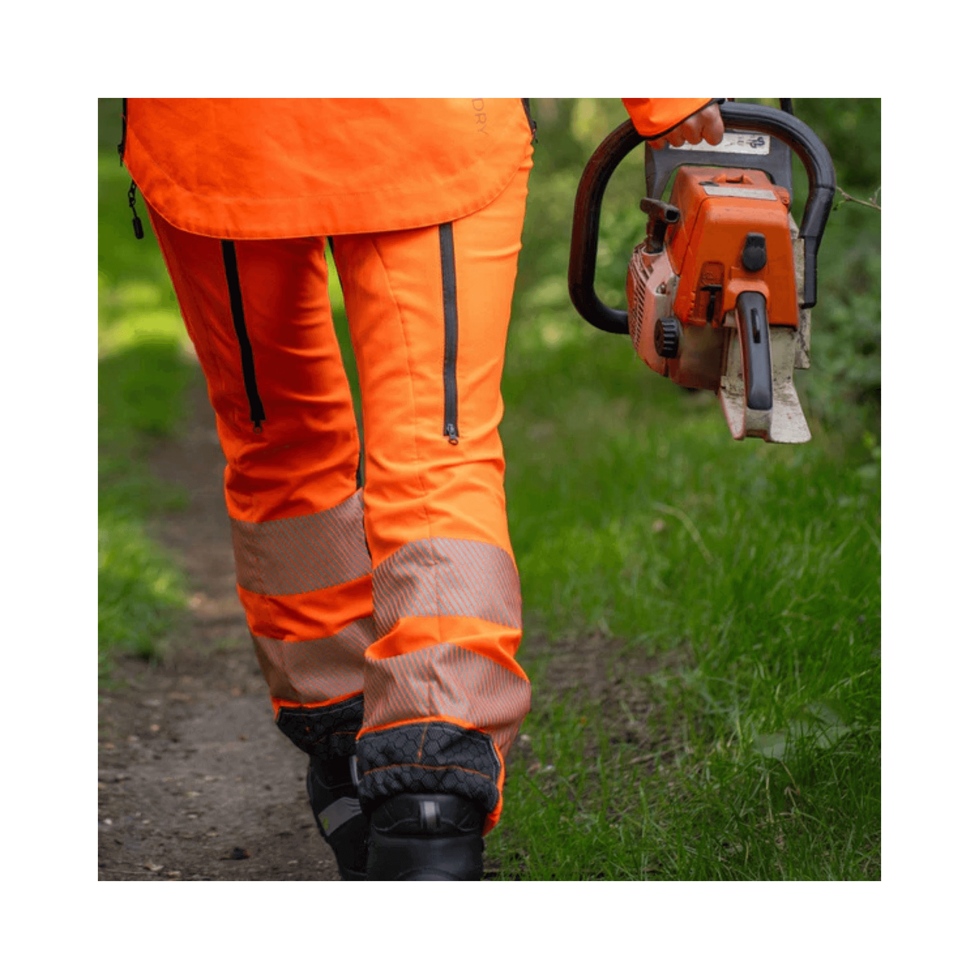 Breatheflex Pro Womens Chainsaw Trousers Type A Hi-Vis Orange worn while carrying a chainsaw on a trail.