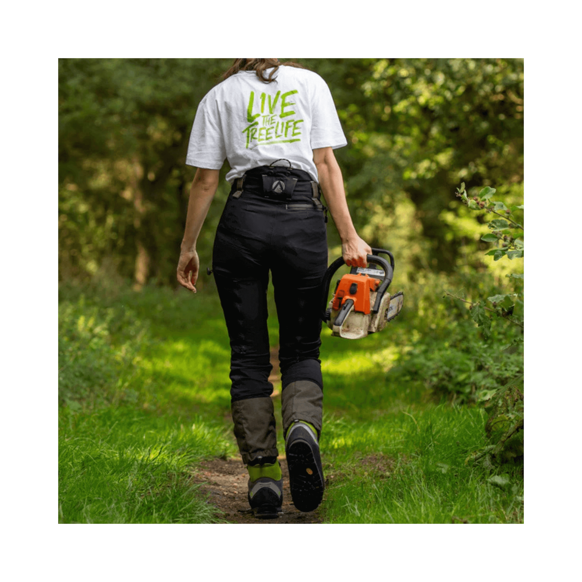 Breatheflex Pro Womens Chainsaw Trousers Type C Black worn by arborist walking on a forest path with chainsaw.