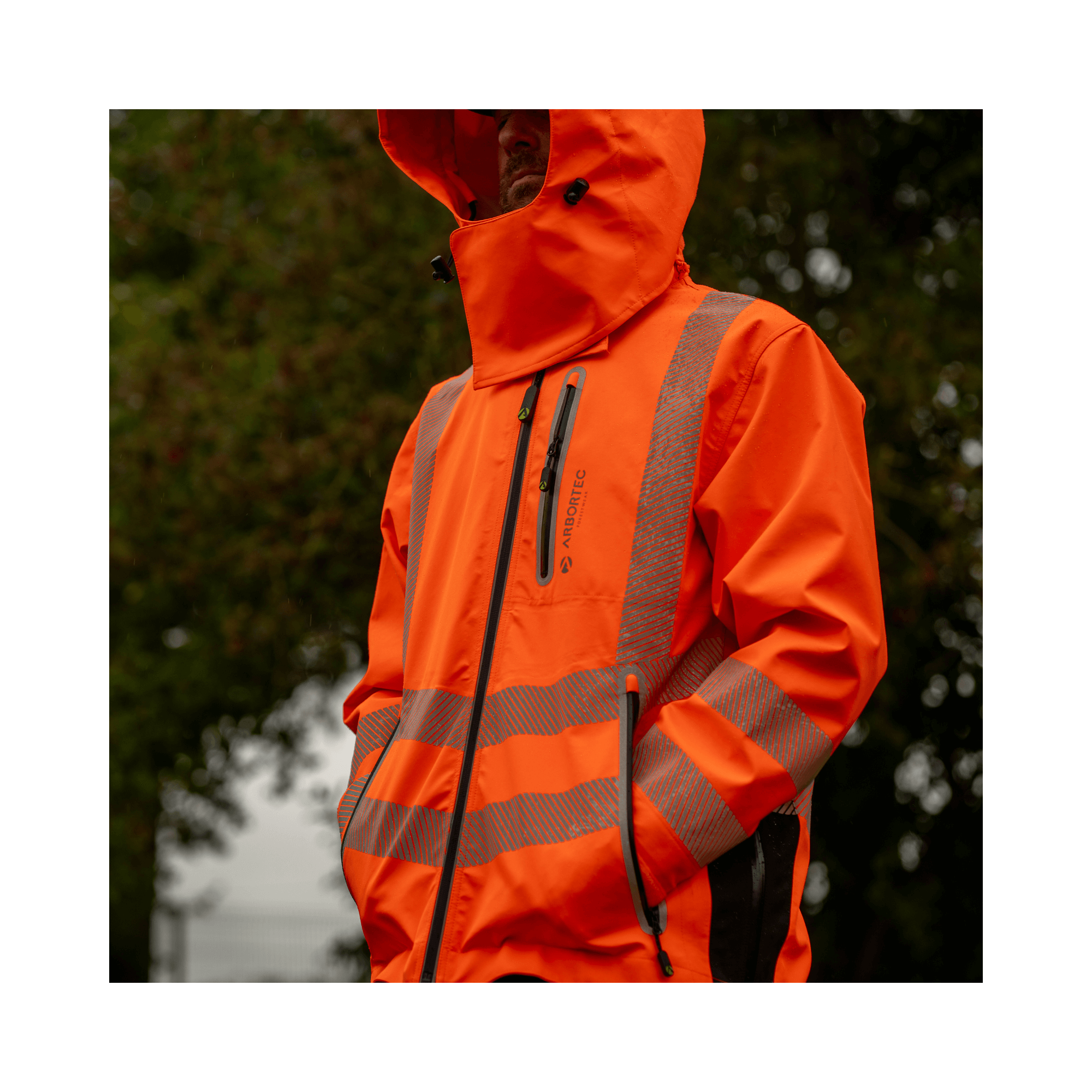 Full Zip Waterproof Work Jacket Hi-Vis Orange worn by a person standing outdoors in a rainy setting.