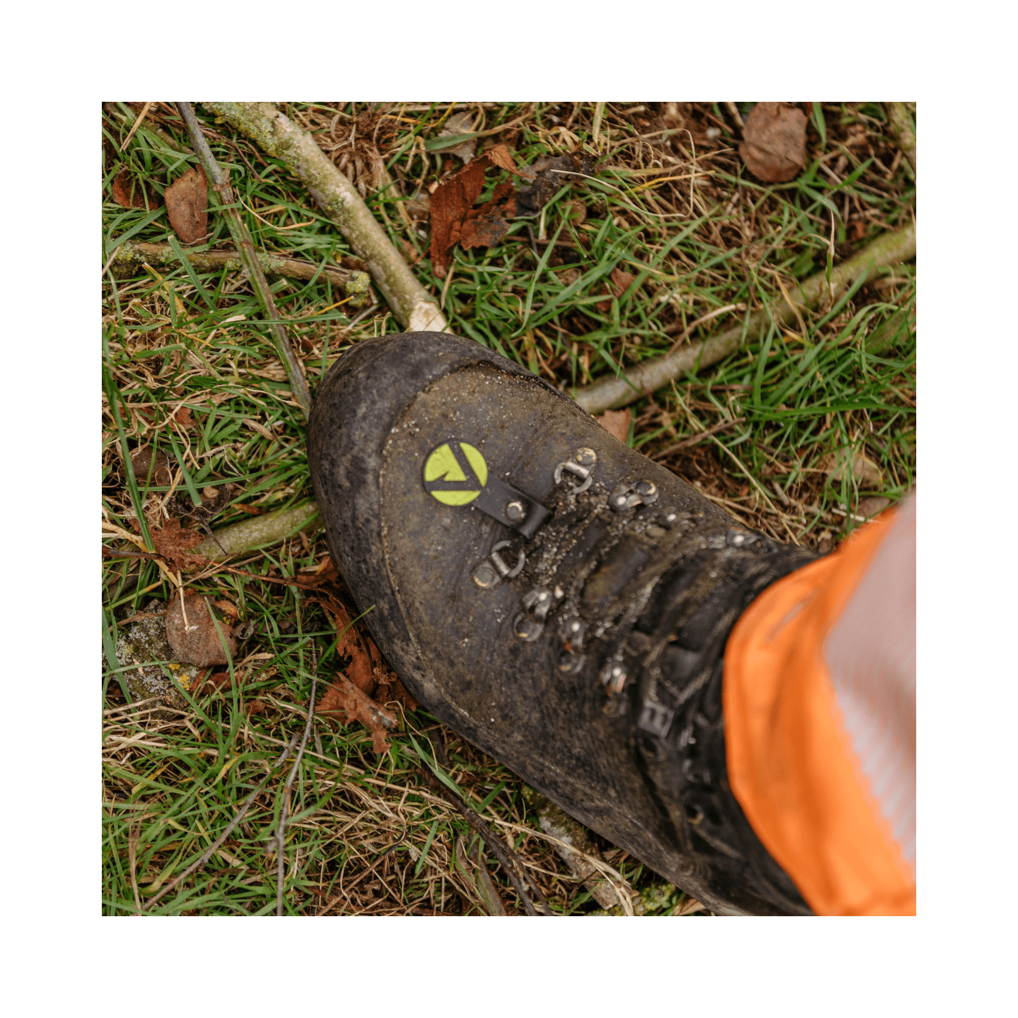 Scafell Lite Chainsaw Boots Class 2 worn by a tree surgeon on the ground among twigs and grass.