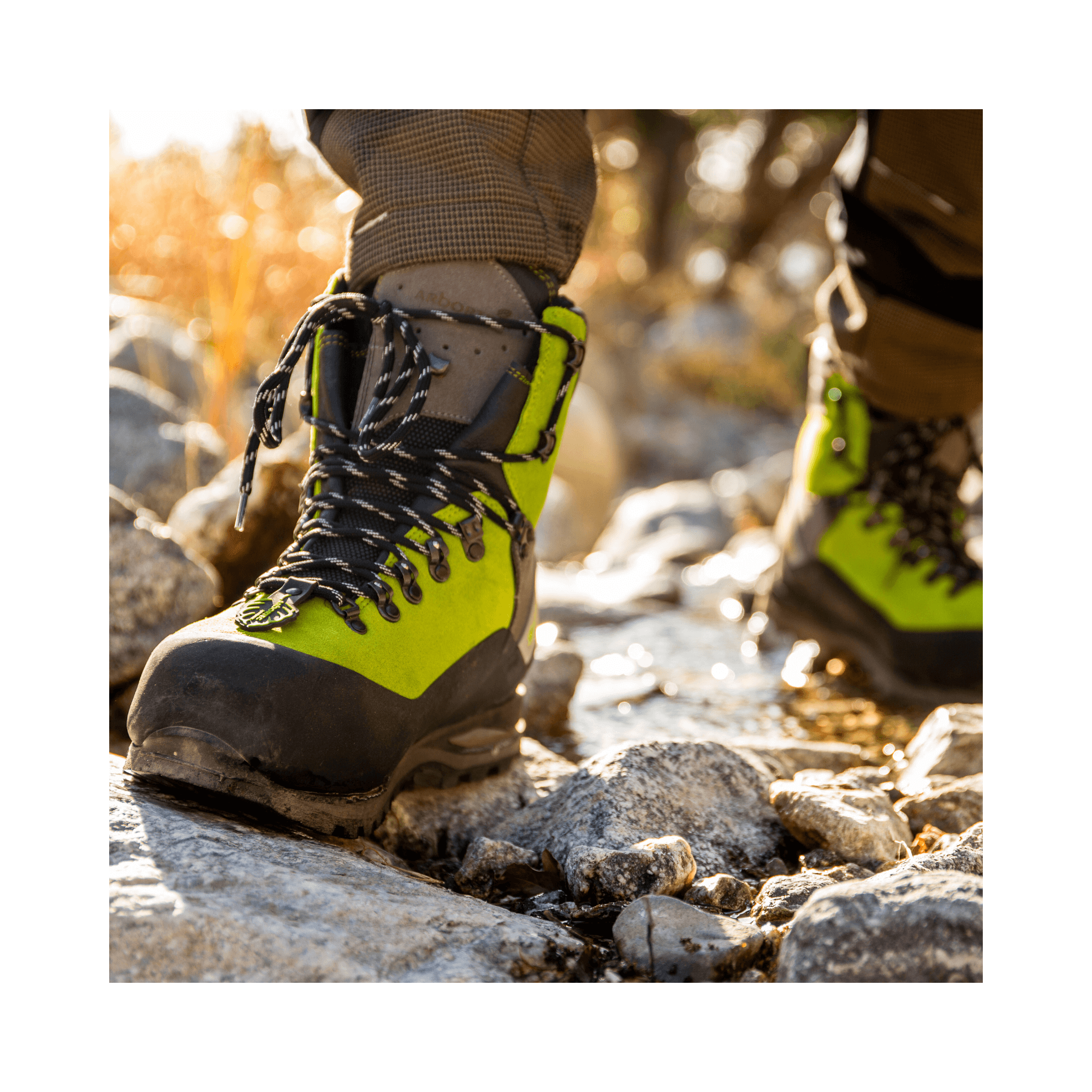 Arbortec Scafell Lite Lime Chainsaw Boots on rocky terrain, designed for tree surgeons and forestry professionals.