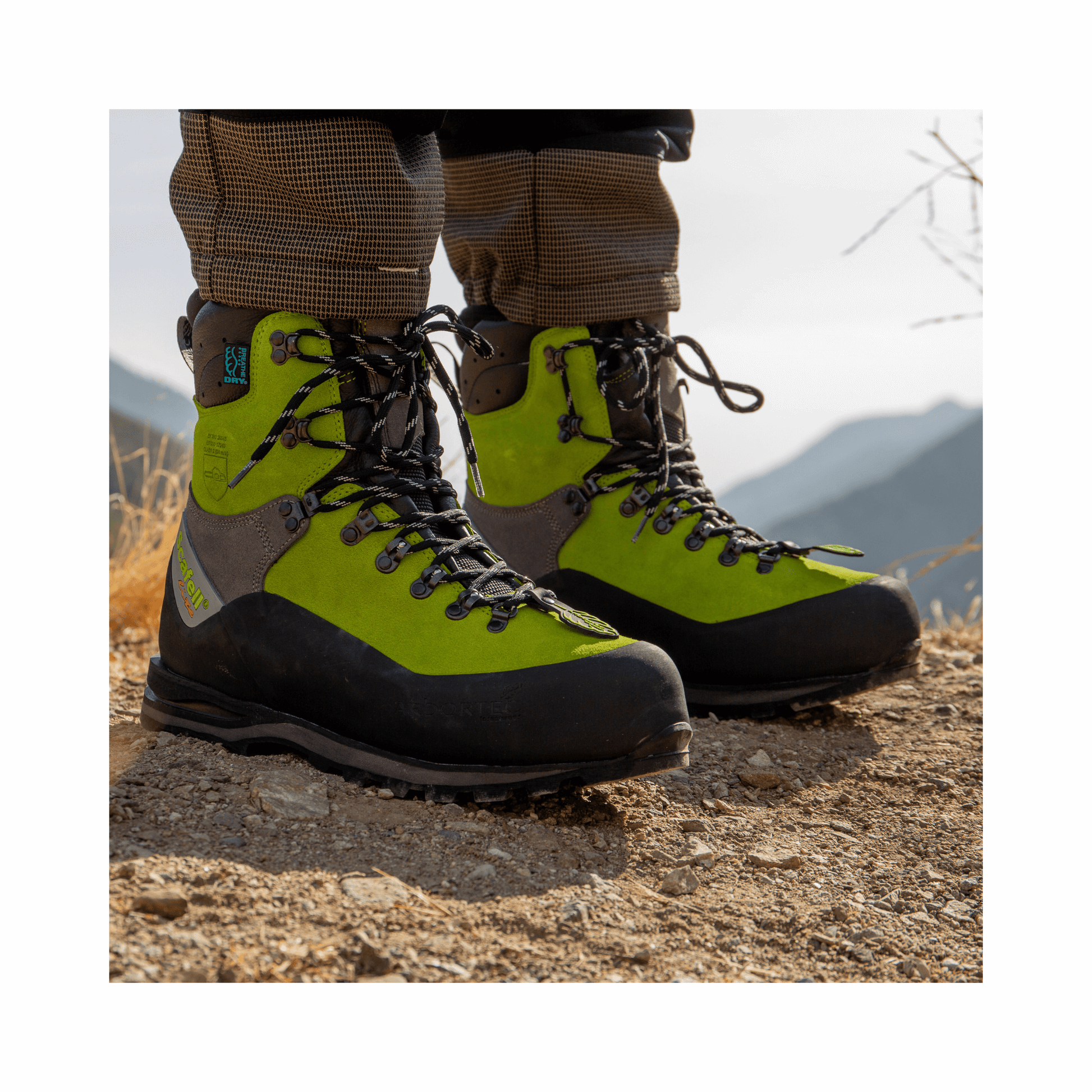 Scafell Lite Lime Chainsaw Boots on a rocky terrain, providing premium safety for tree surgeons in forestry.