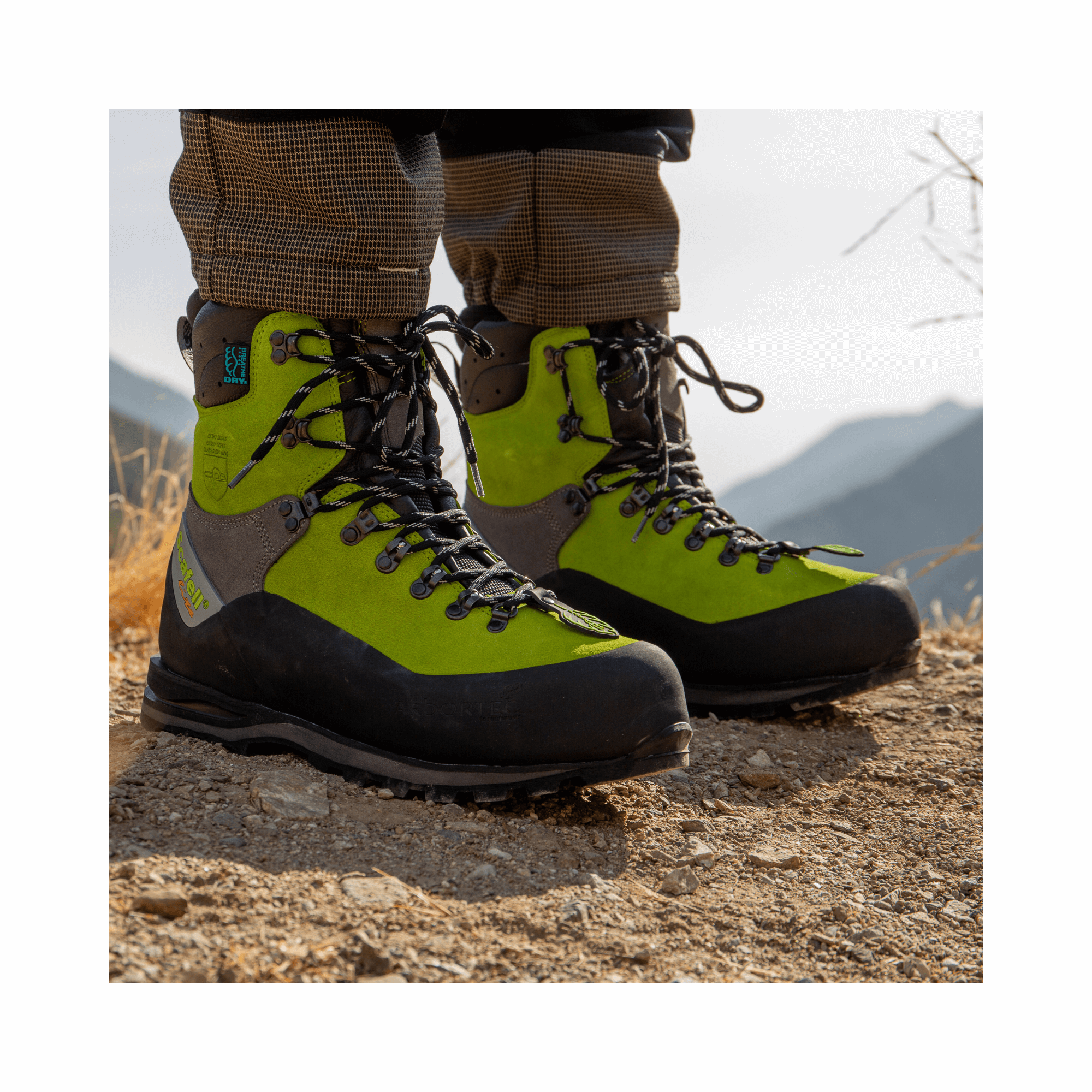 Scafell Lite Lime Chainsaw Boots on a rocky terrain, providing premium safety for tree surgeons in forestry.