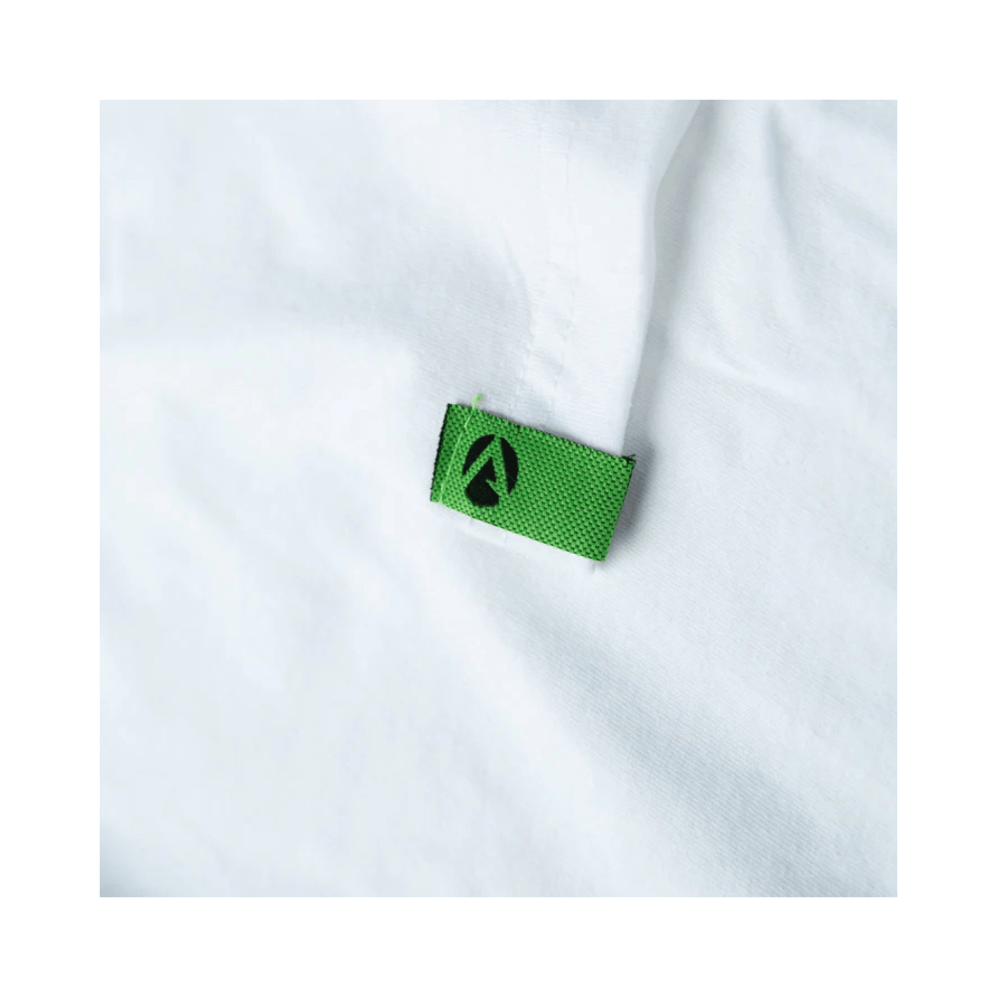 Close-up of the label on the Arbortec Short Sleeve T-Shirt White, featuring a green tag with the Arbortec logo.